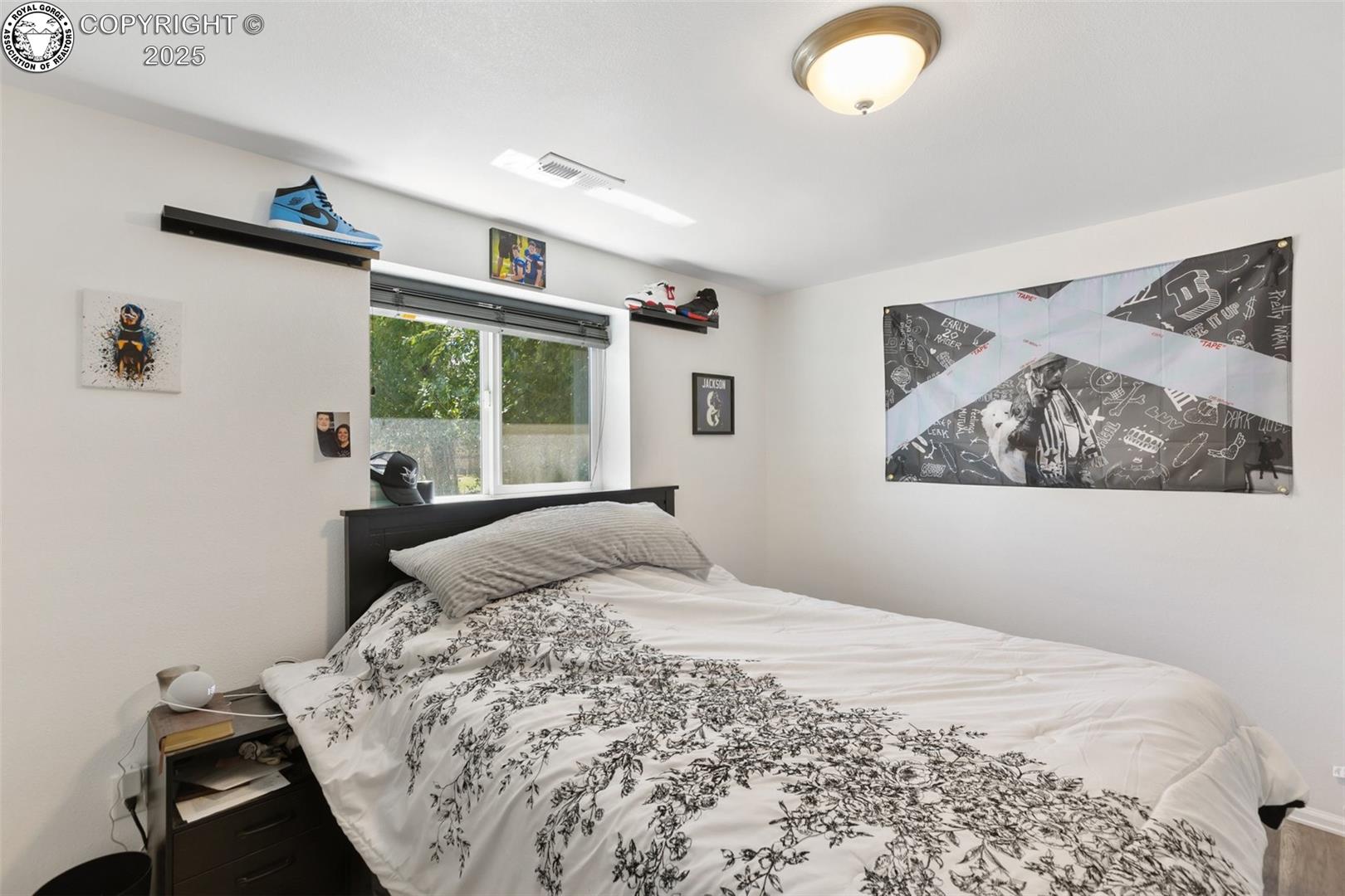 Bedroom with floral bedding, a window, and sports-themed wall art.