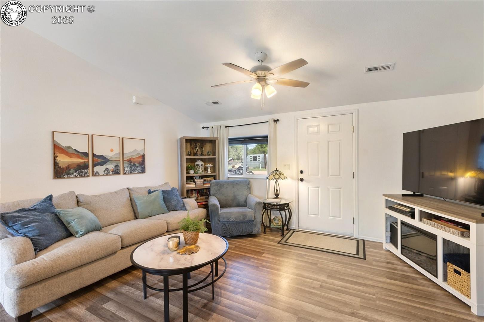 Living room with a beige sectional, blue armchair, round coffee table, and television.