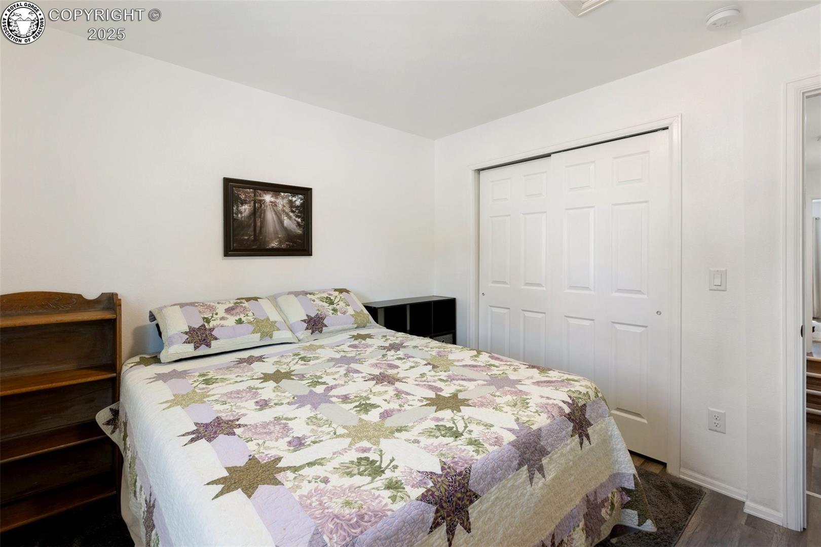 Furnished bedroom with a floral star-pattern quilt and white sliding closet doors.