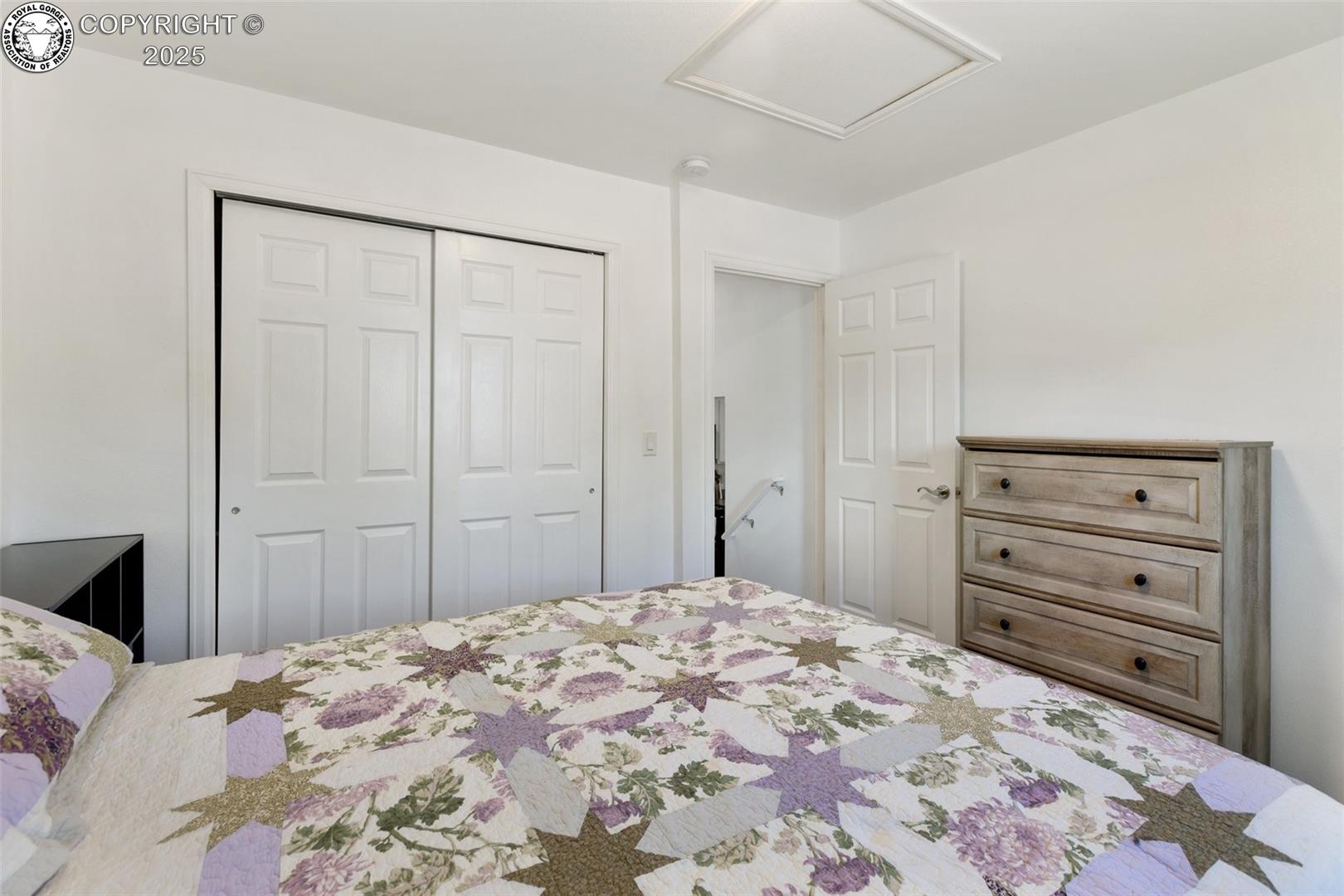 Bedroom with a floral patchwork quilt, sliding closet doors, and a wood-tone dresser.