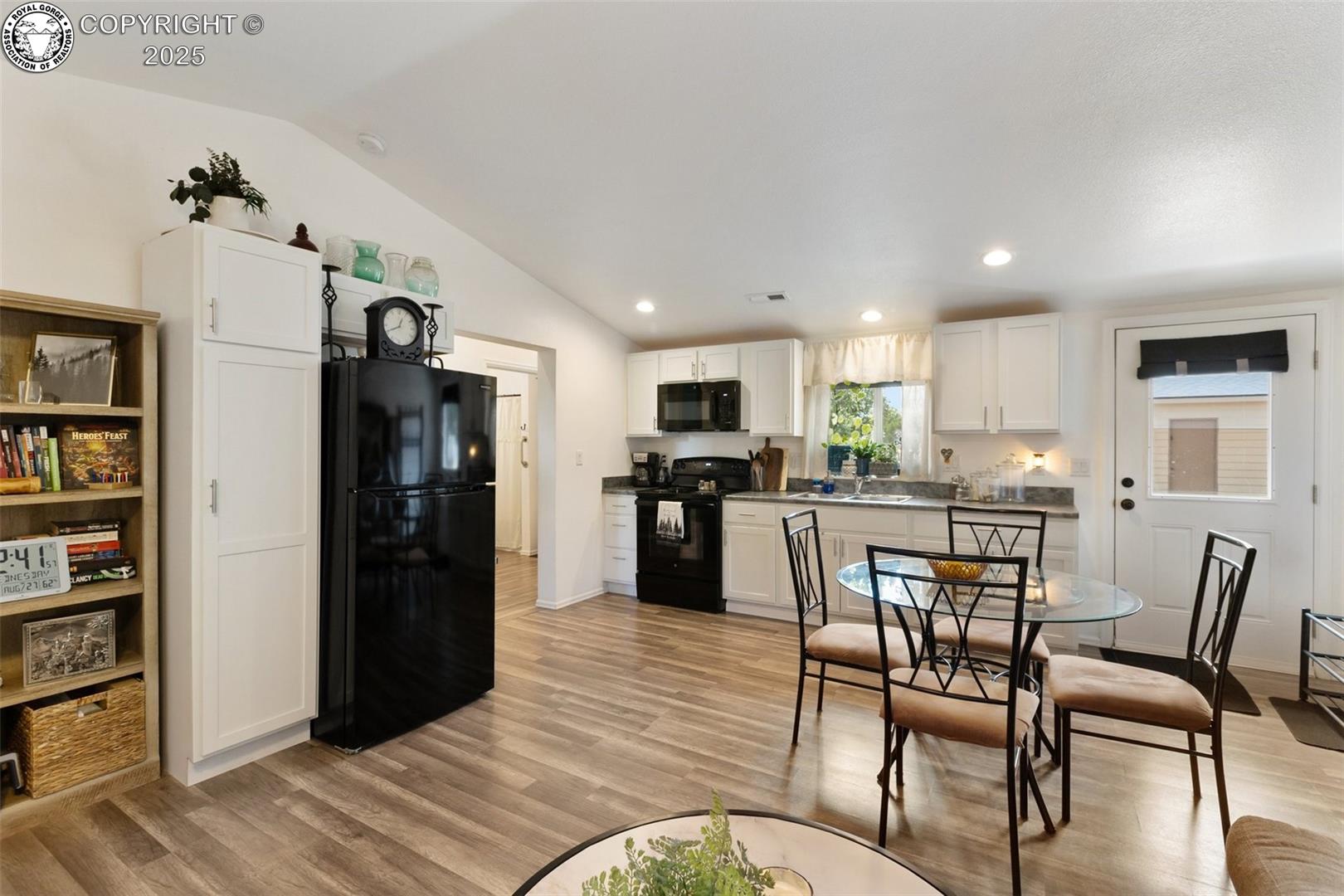 Kitchen and dining area with white cabinets, black appliances, and a glass-top table.