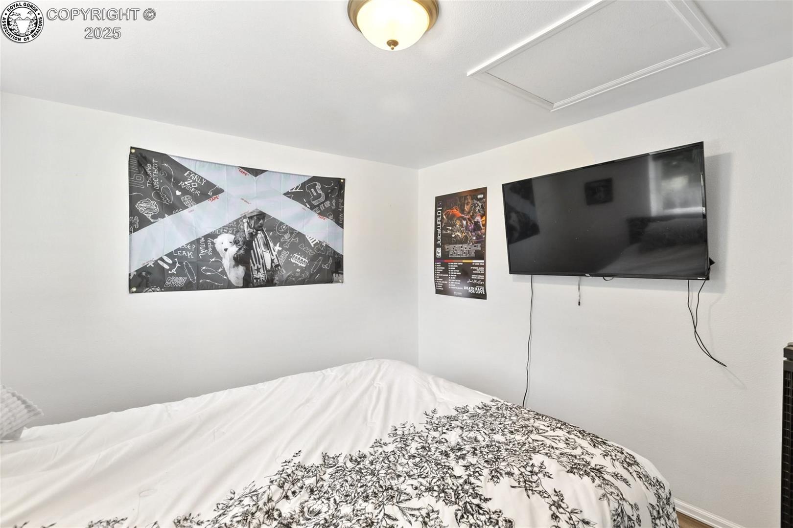 Bedroom with black-and-white floral bedding, a wall-mounted TV, and music posters.