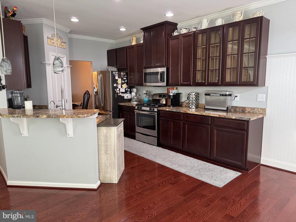 Kitchen with cherry cabinets, granite counters, stainless steel appliances, and hardwood floors.