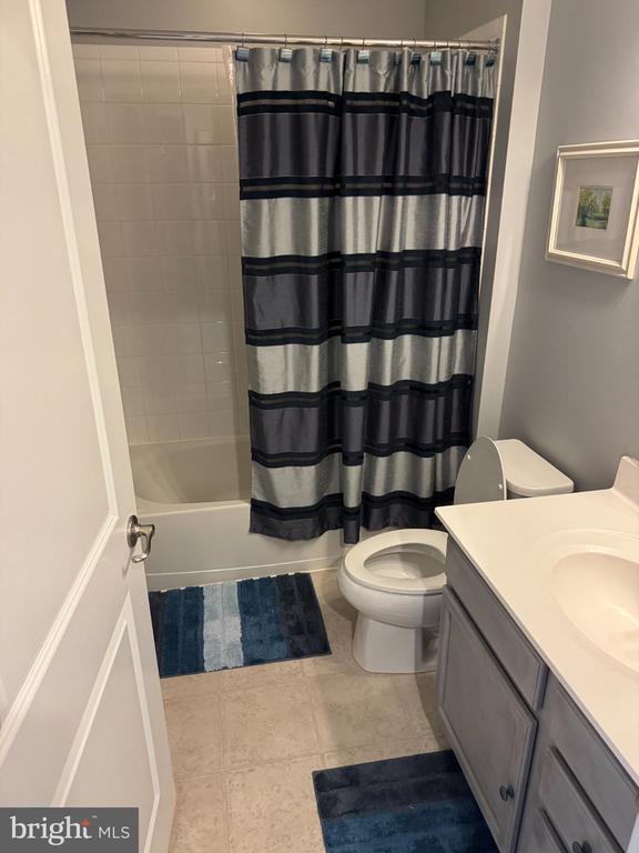 Bathroom with a striped shower curtain, toilet, and white vanity.