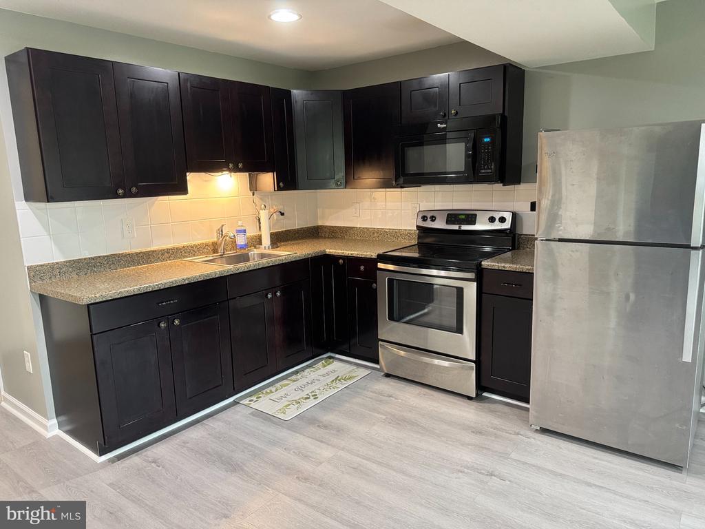 Kitchen with dark cabinets, speckled countertops, and stainless steel appliances.