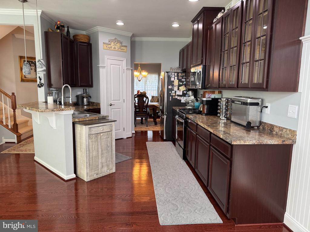 Kitchen with dark cherry cabinets, granite counters, stainless steel appliances, and a breakfast bar.