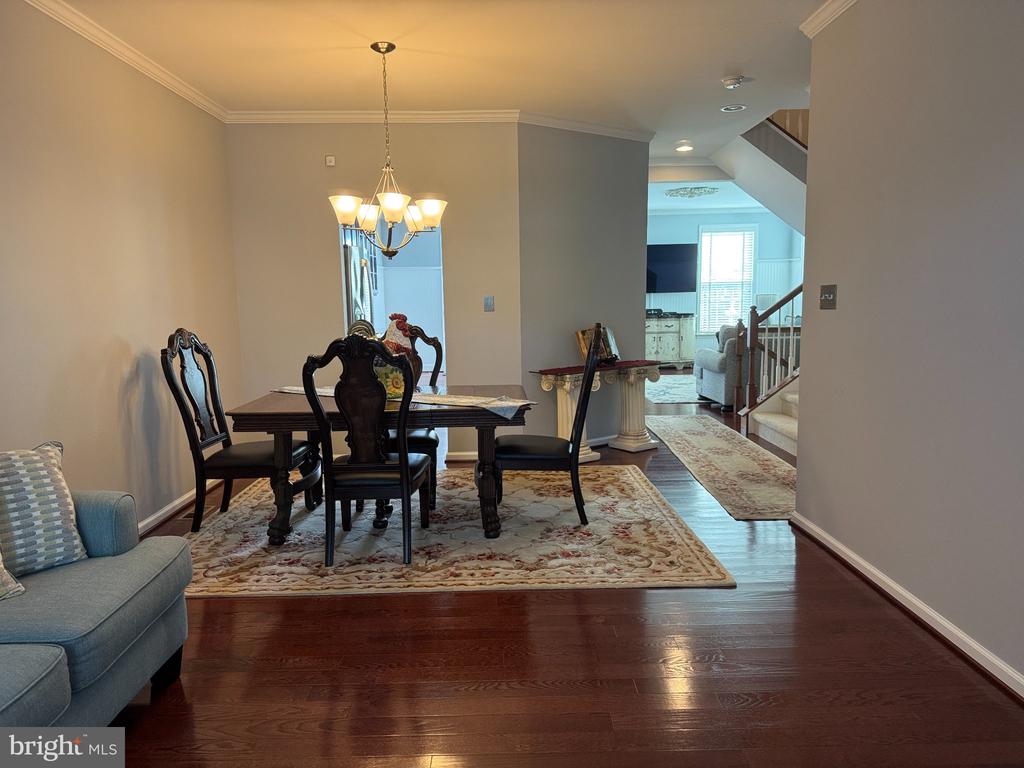 Dining room with a dark wood table, chandelier, patterned rug, and view toward the living room and staircase.