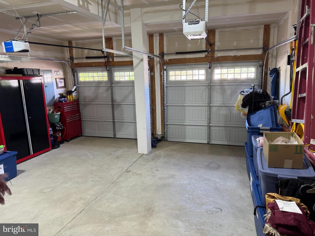 Garage with two overhead doors, a concrete floor, and storage bins along the side.