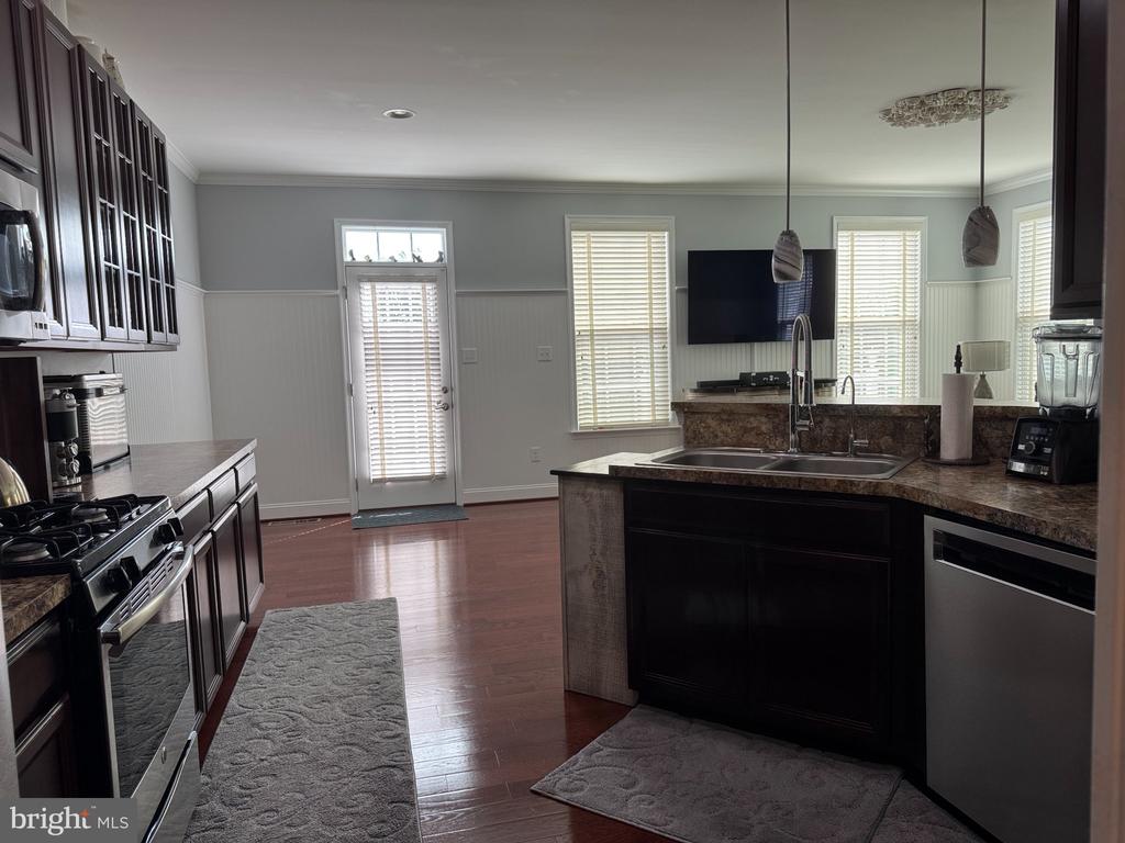 Kitchen with dark wood cabinets, stone counters, central sink island, and hardwood floors.