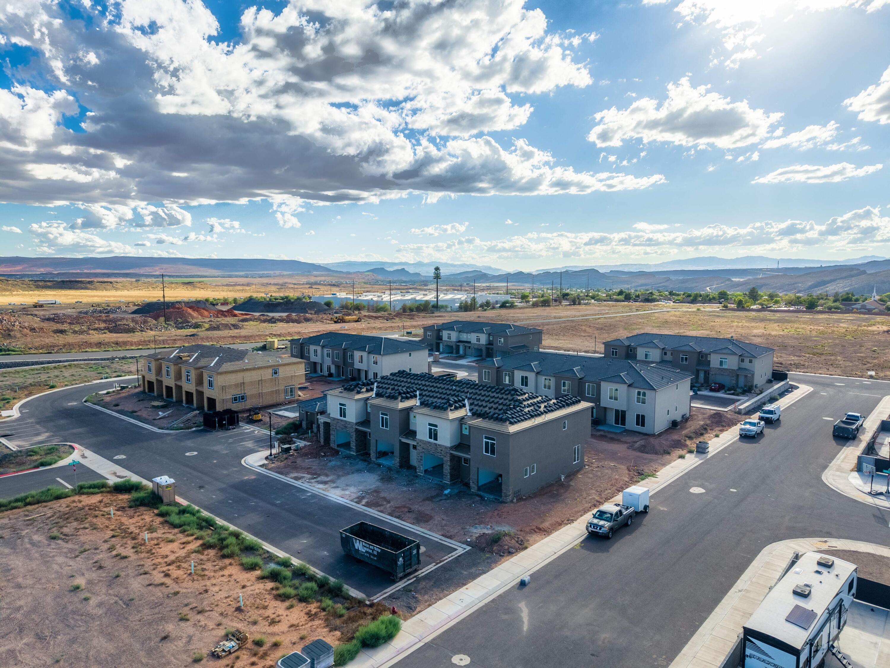 Aerial view of new homes under construction with distant mountains and open desert terrain.