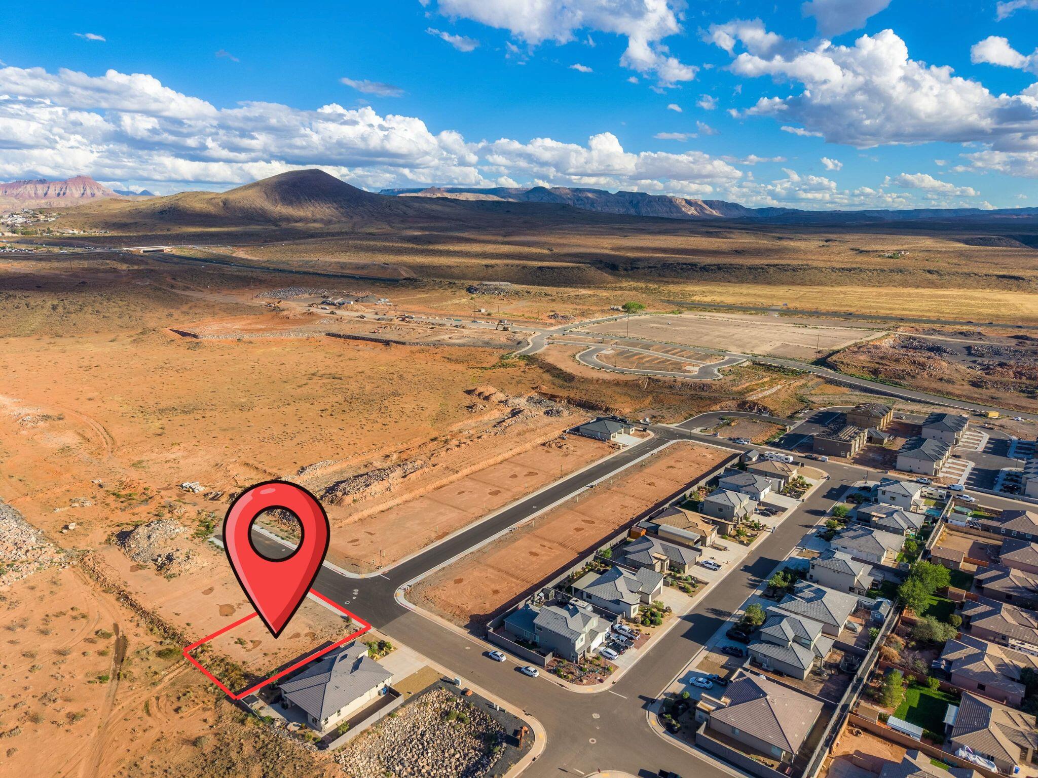 Vacant desert lot outlined in red beside a neighborhood, with distant mountain ridges.