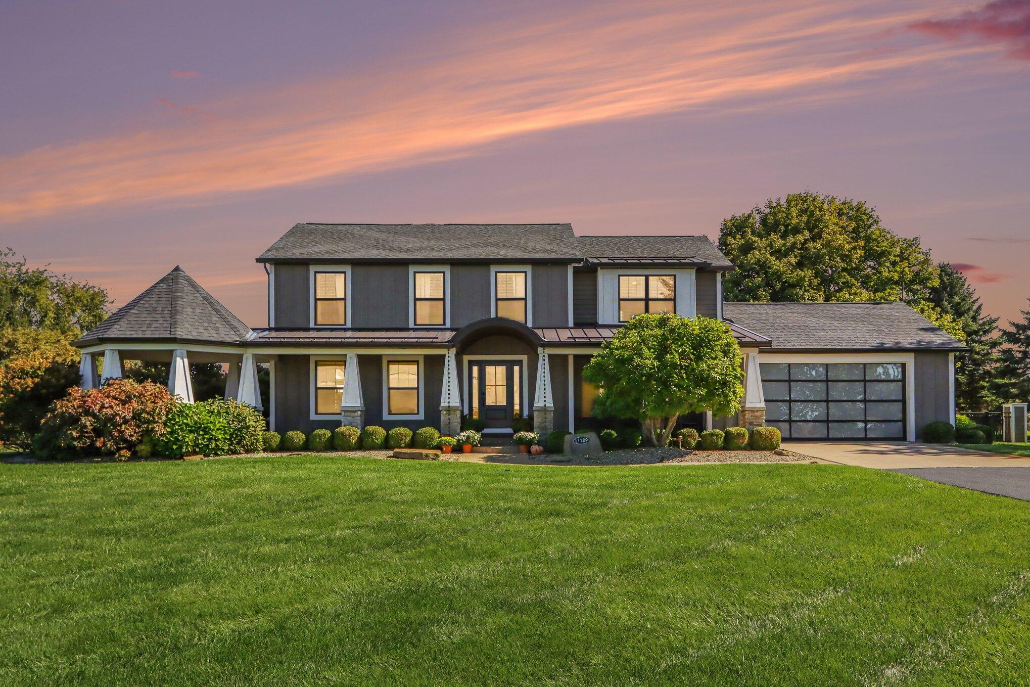 Two-story gray house with a covered porch and attached garage at dusk.