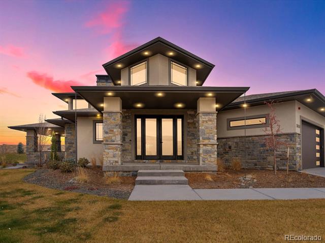 Modern luxury home with stone-and-stucco exterior and angular roof at dusk.