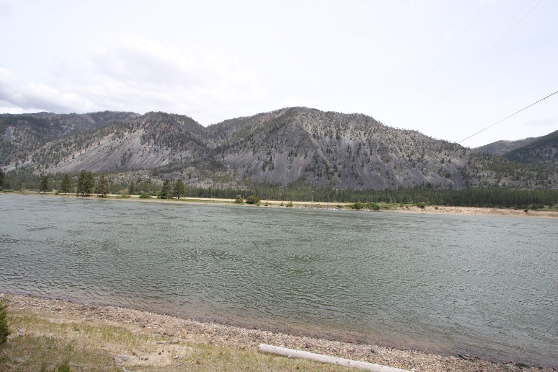 Riverfront land across from a forested mountain range.