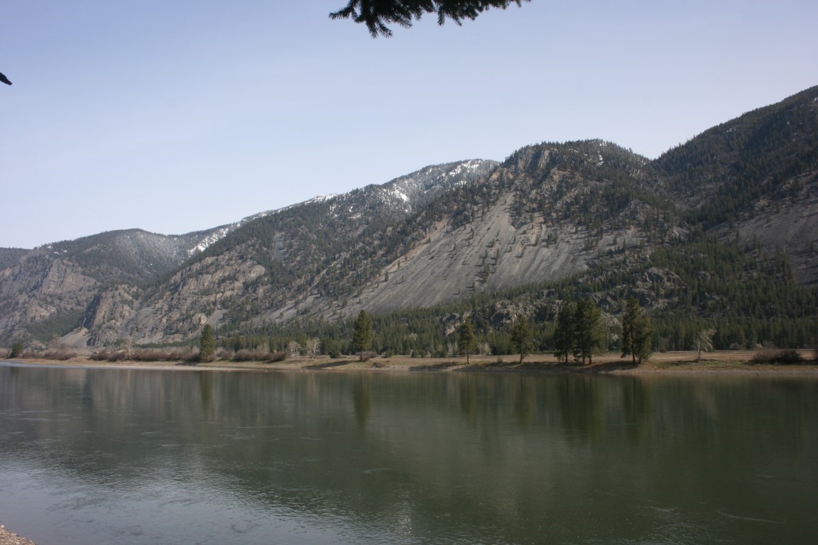 River and wooded mountains with rocky slopes and patches of snow
