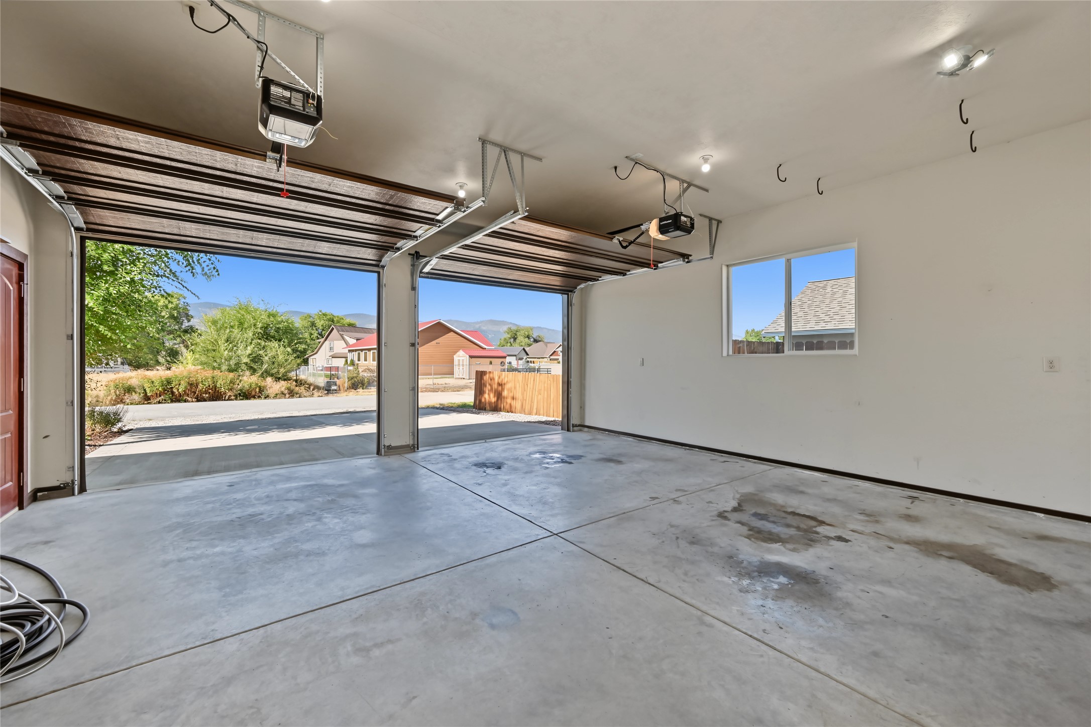 Vacant two-car garage with two open doors and distant mountains visible outside.