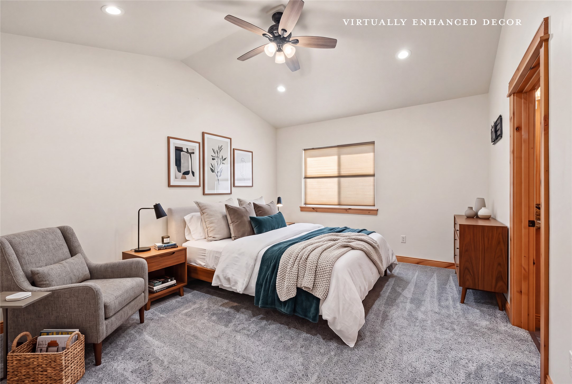 Staged bedroom with a teal-accented bed, gray armchair, and vaulted ceiling.