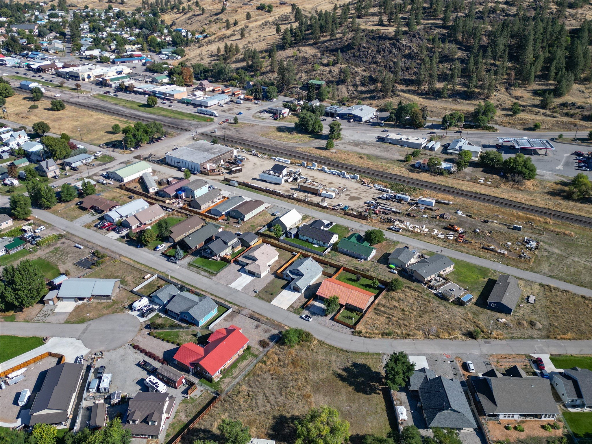 Aerial view of town homes, commercial buildings, railroad tracks, and wooded hills.