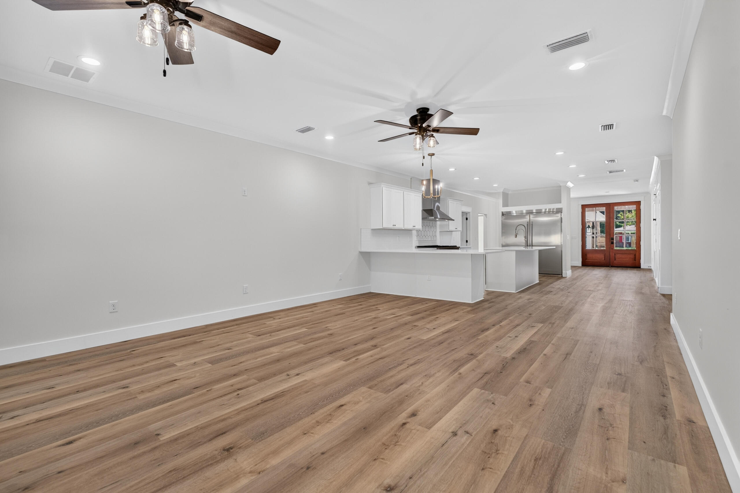 Open-plan living area and kitchen with a large island, stainless appliances, and wood-framed glass doors.