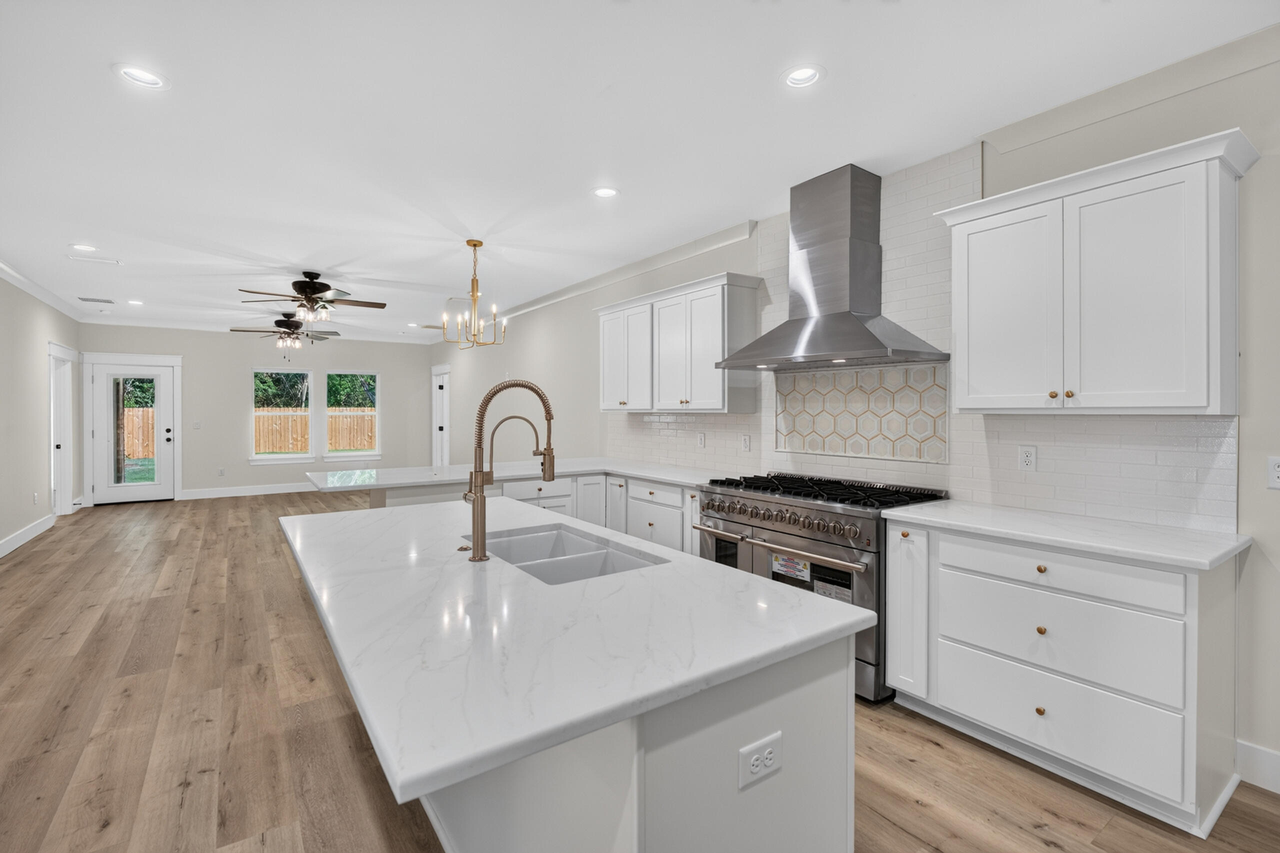Bright kitchen with a large stone island, white cabinets, and a stainless steel range.