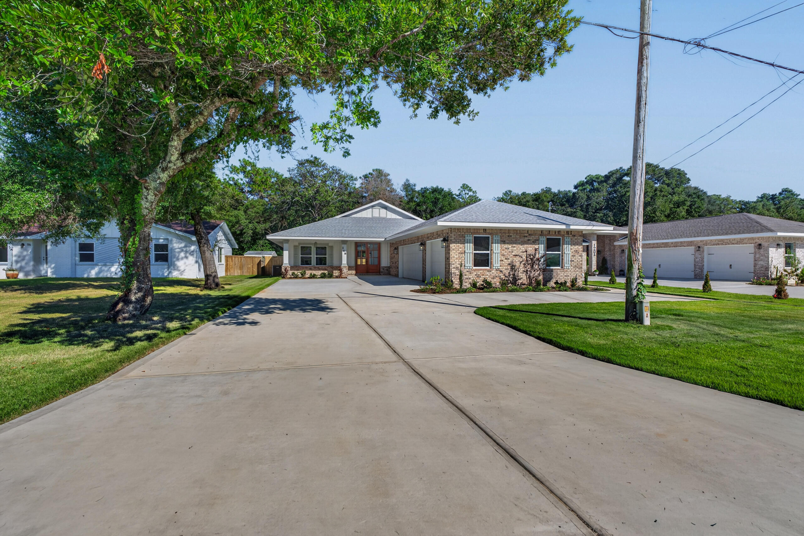 Single-story brick-and-siding home with a broad concrete driveway and mature trees.