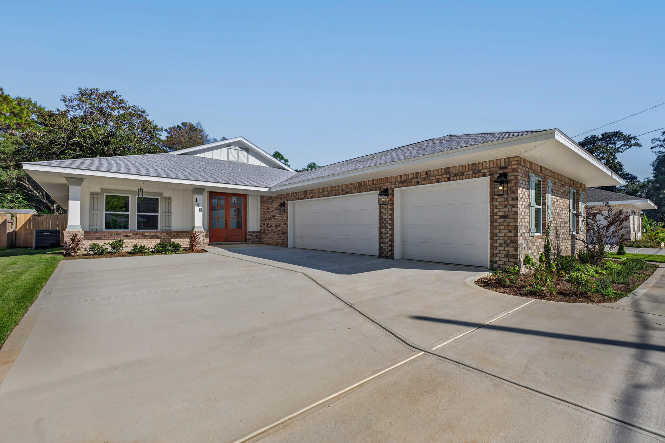 Single-story brick home with a wide driveway, two-car garage, and reddish-brown double entry doors.