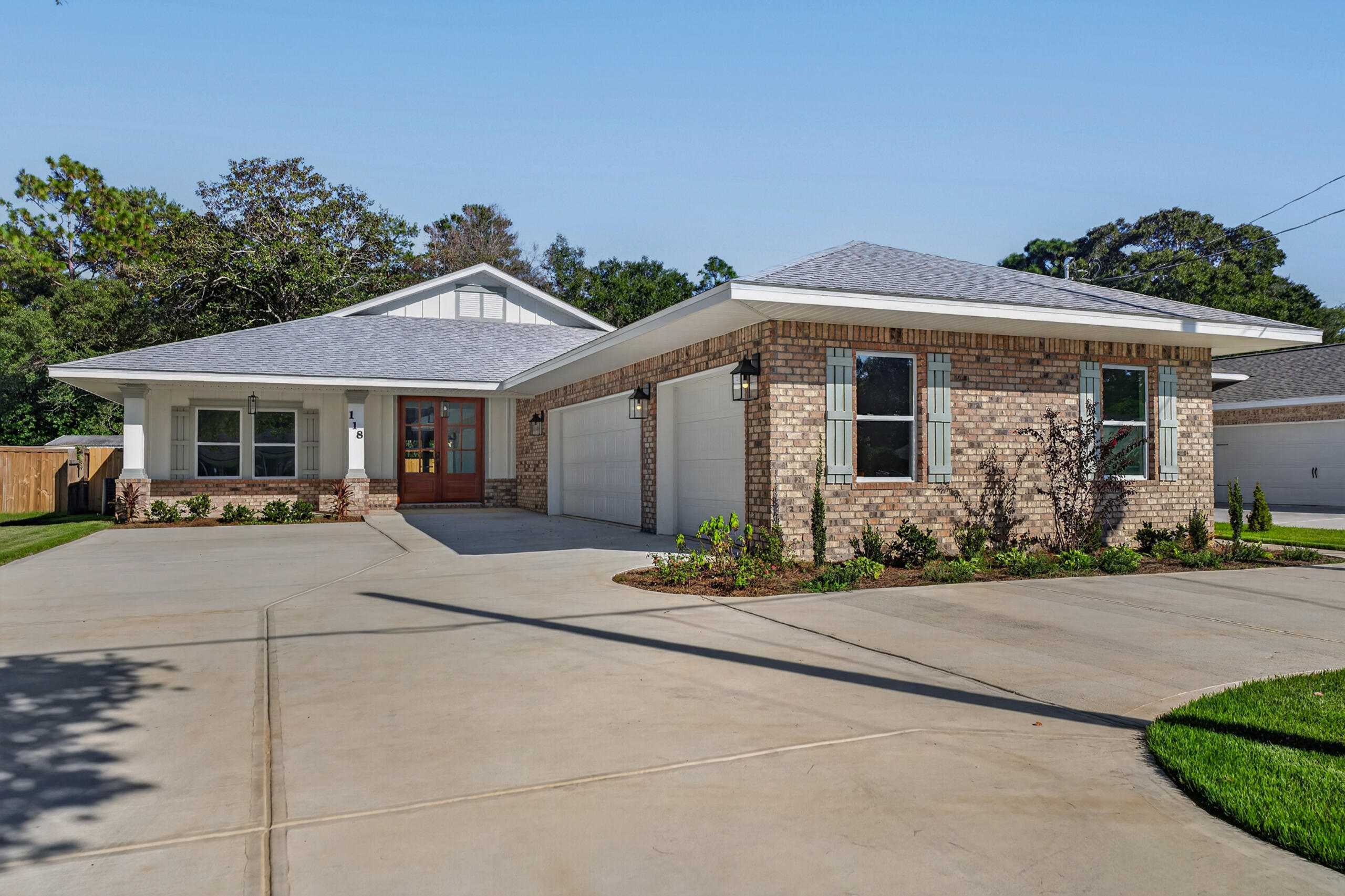 Single-story brick home with a two-car garage, wide driveway, and landscaped front beds.