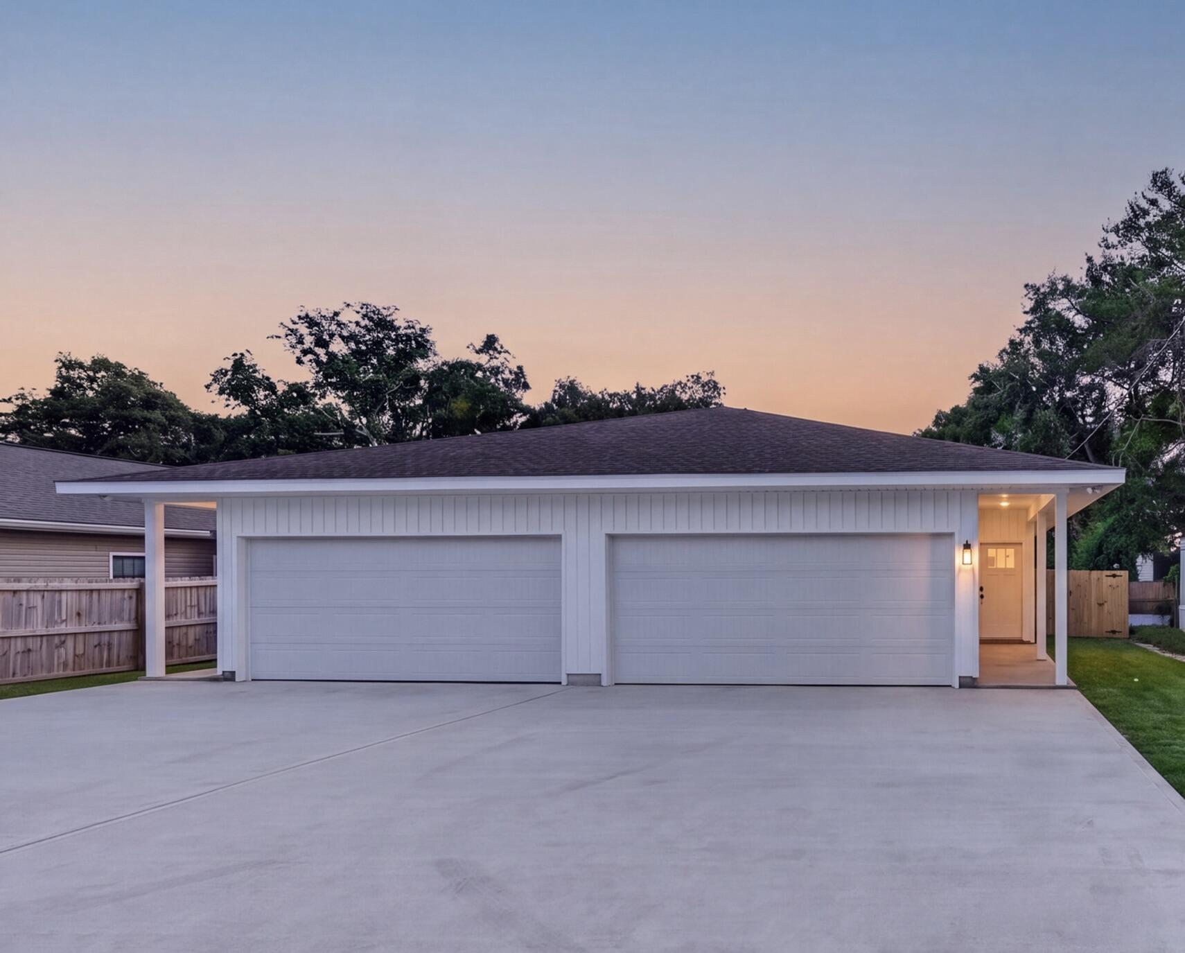 Home exterior with two garage doors and a lit covered entry at dusk.