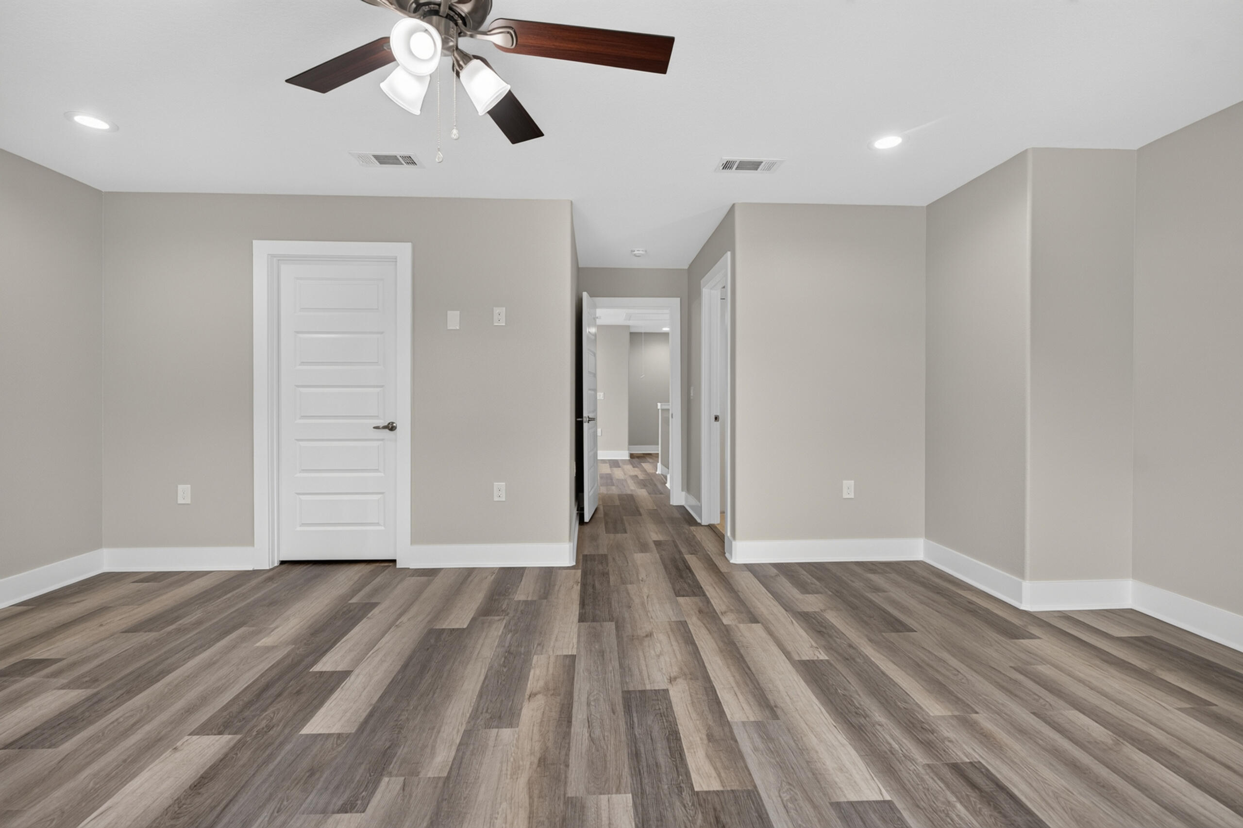 Empty room with wood-look plank flooring, a ceiling fan, and an open doorway to the hall.