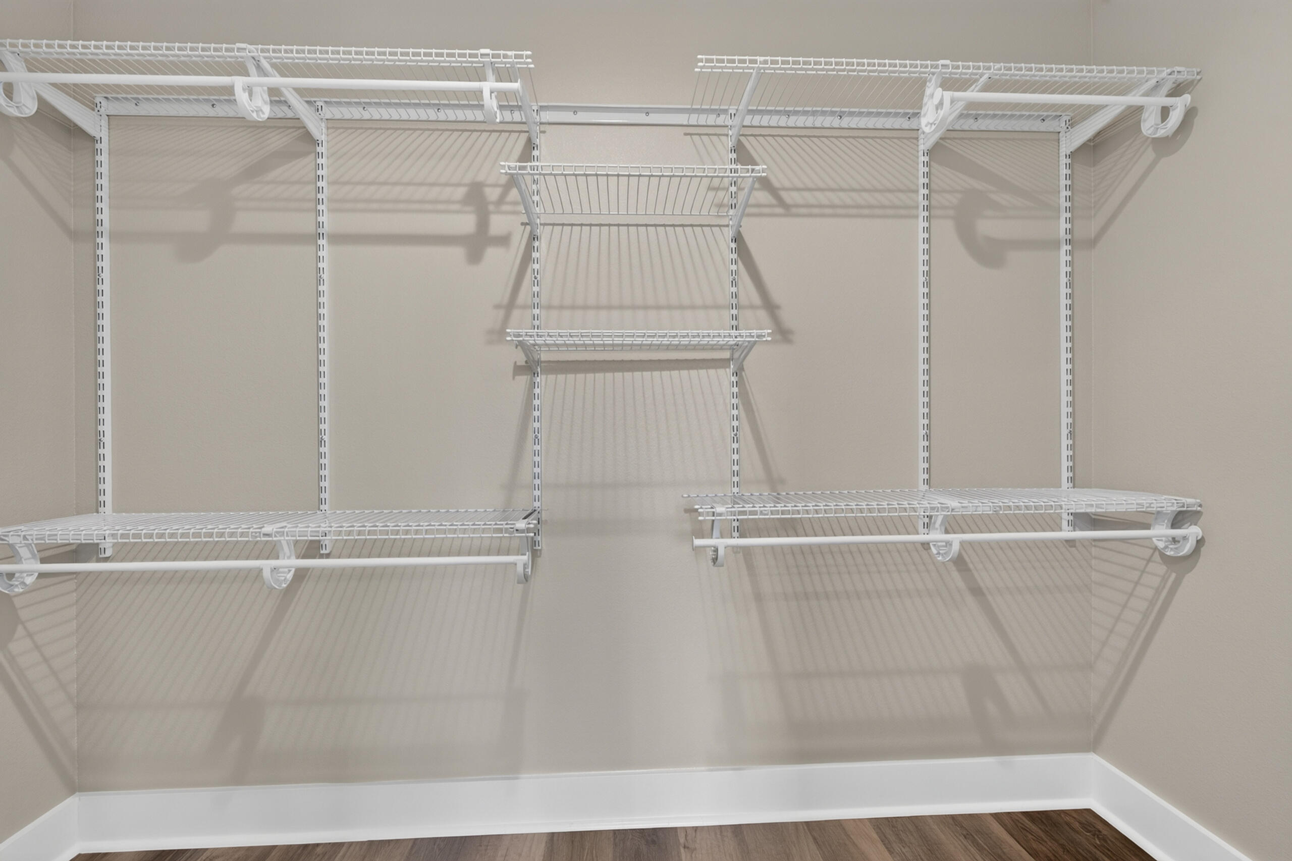 Empty walk-in closet with extensive white wire shelving and hanging rods.