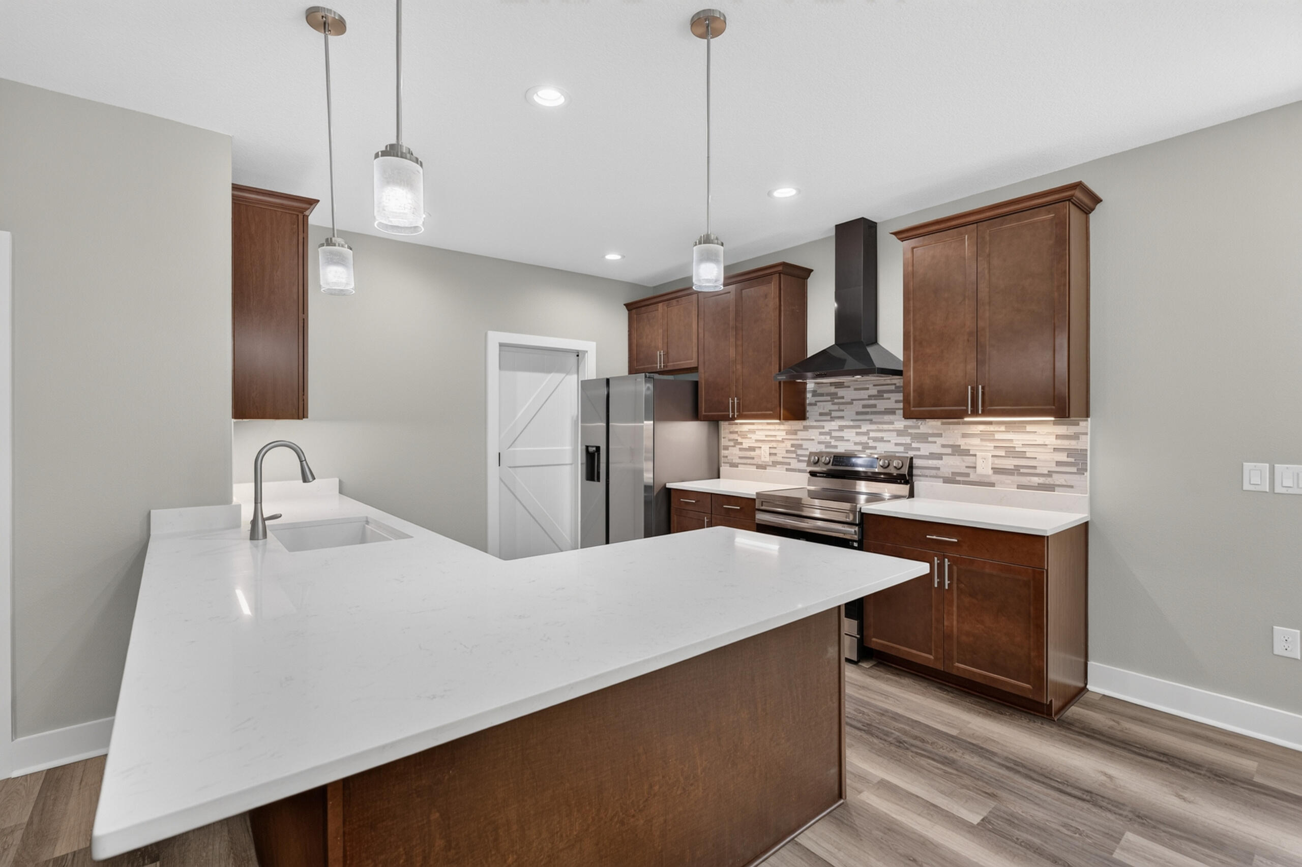 Kitchen with a large white quartz island, dark wood cabinets, and stainless steel appliances.