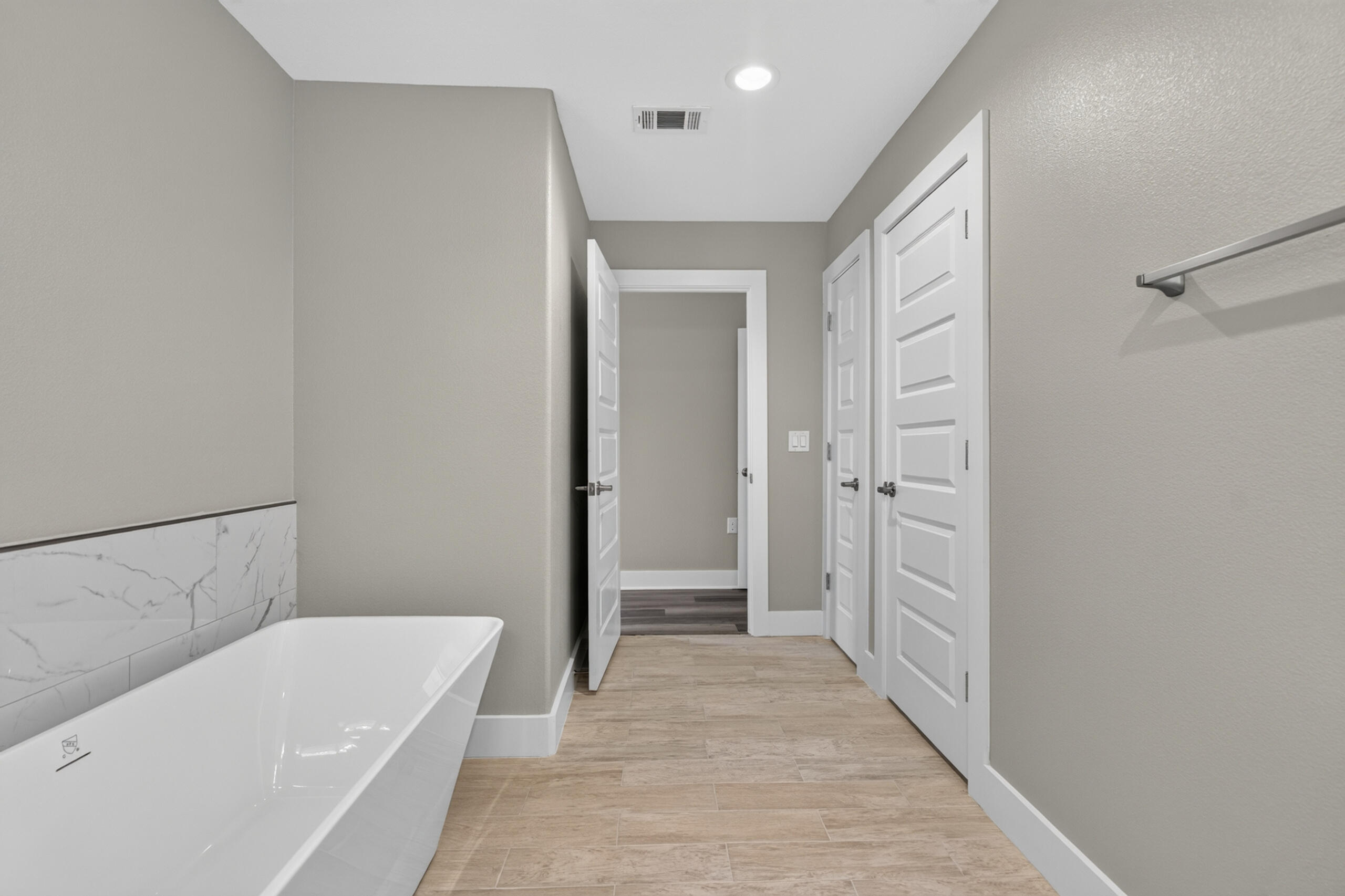 Bathroom with a freestanding tub, marble-look tile, and beige tile flooring.