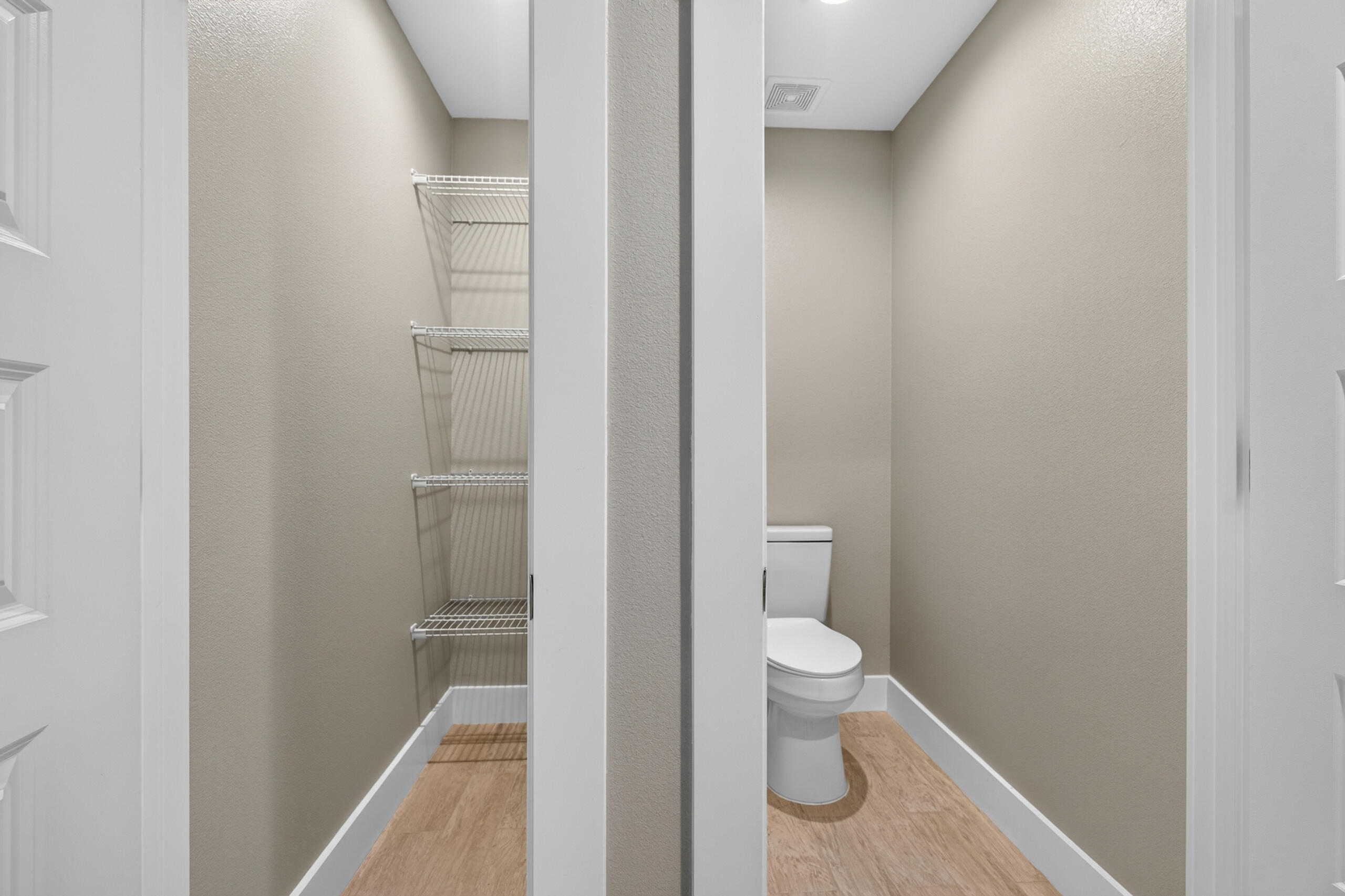 Bathroom with a toilet and an adjacent open closet with wire shelves.