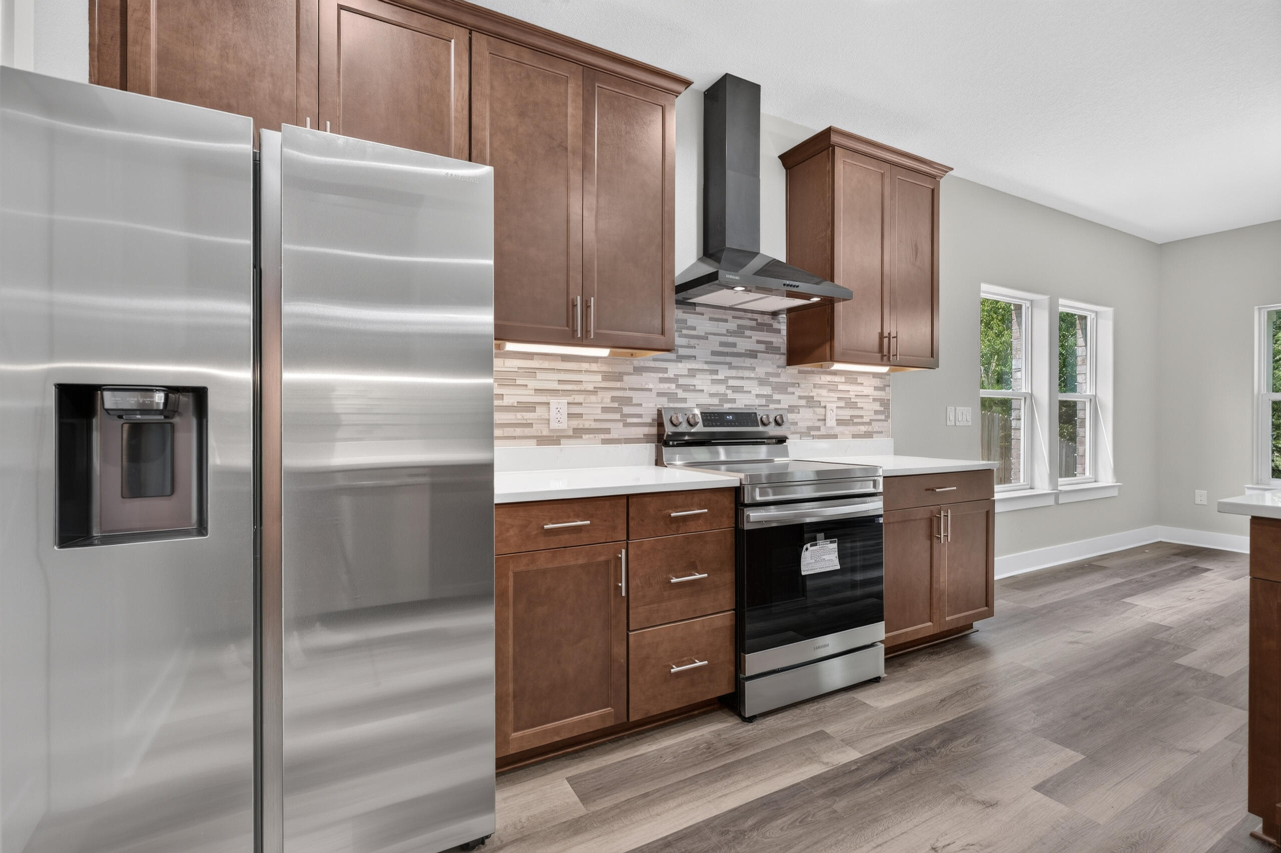 Kitchen with brown cabinets, stainless steel appliances, and a patterned tile backsplash.