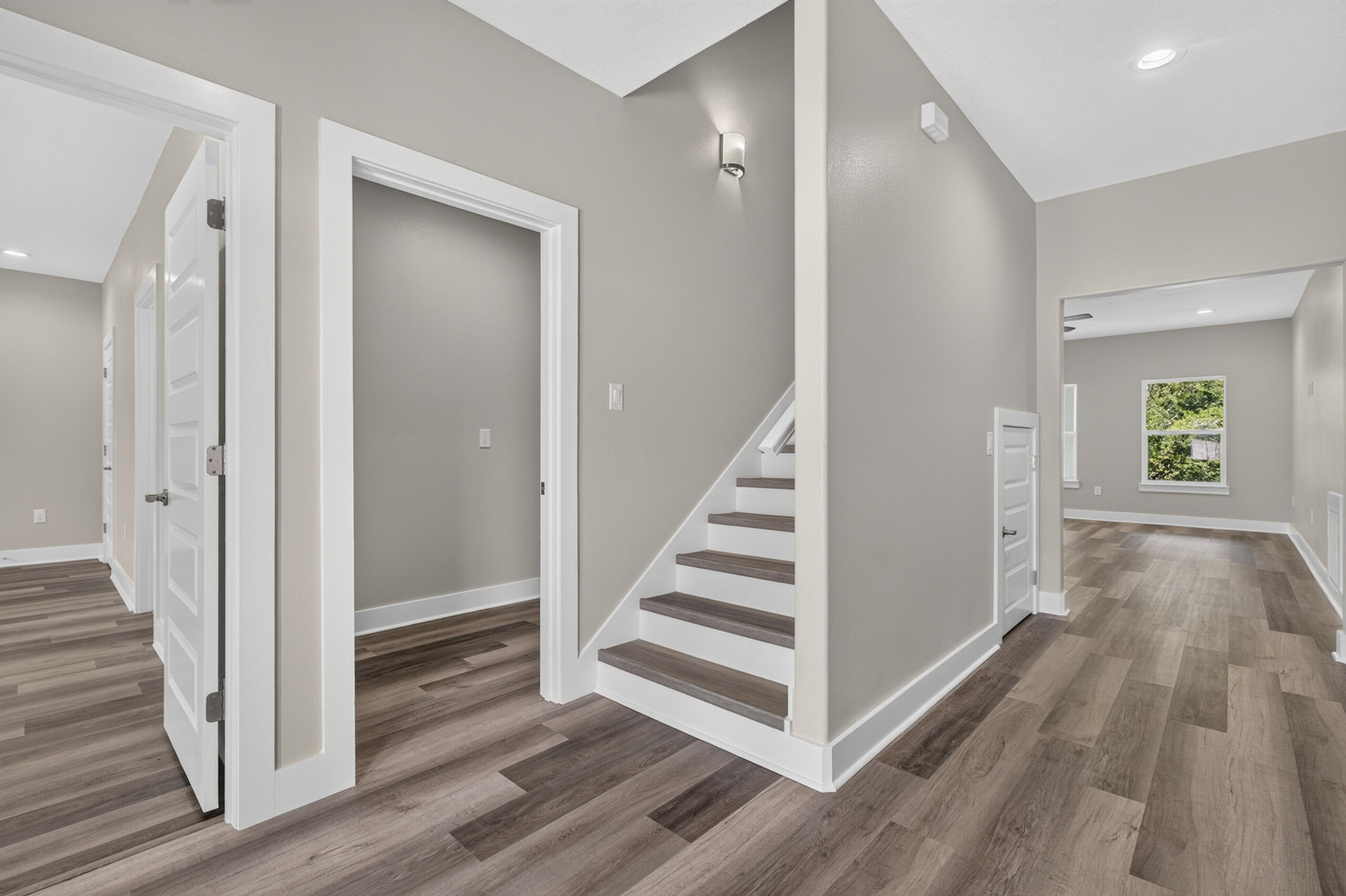Entry hall with wood-look floors, white-trimmed doorways, and a staircase with dark treads.
