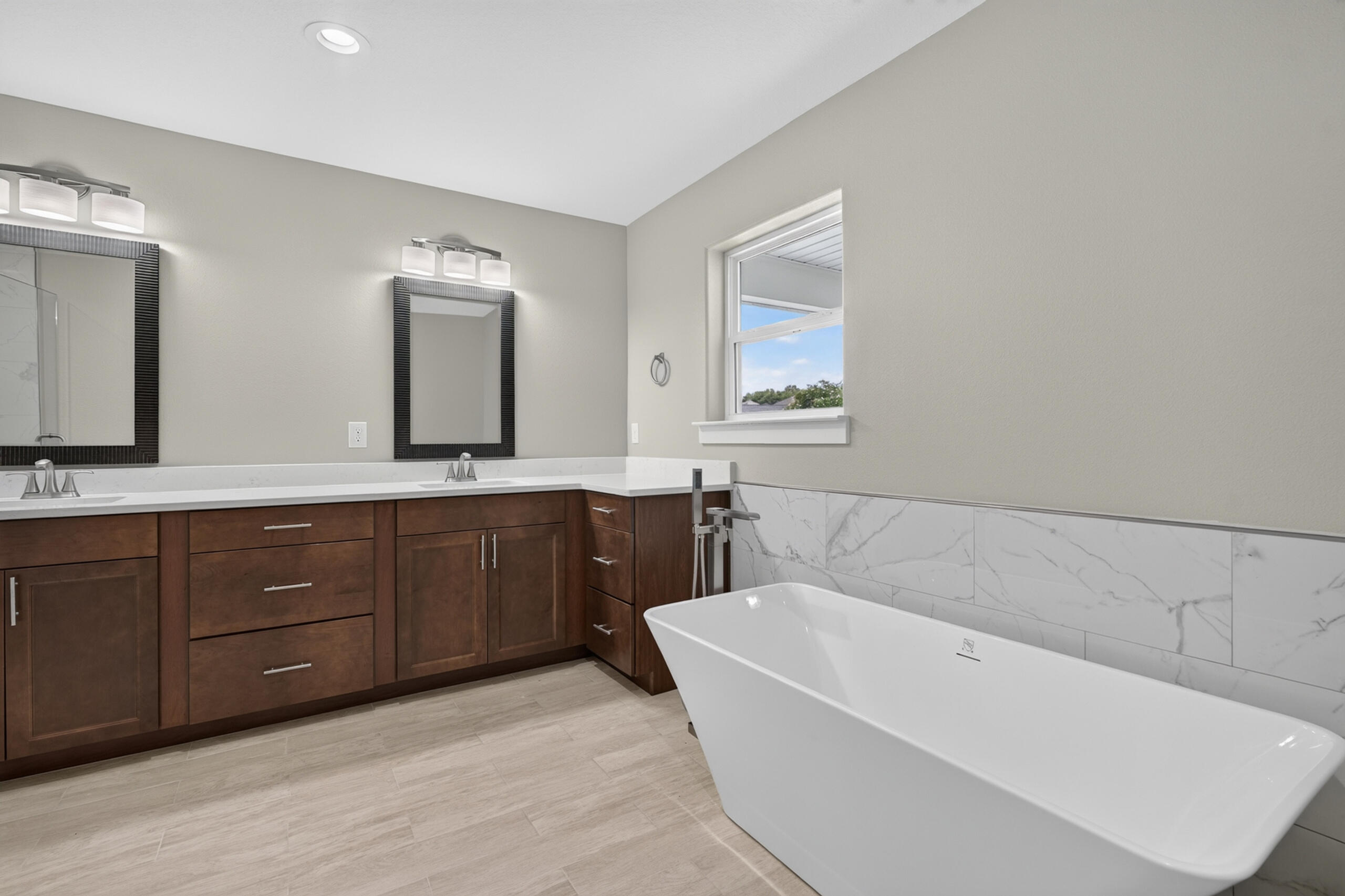 Modern bathroom with a freestanding soaking tub and long double-sink wood vanity.