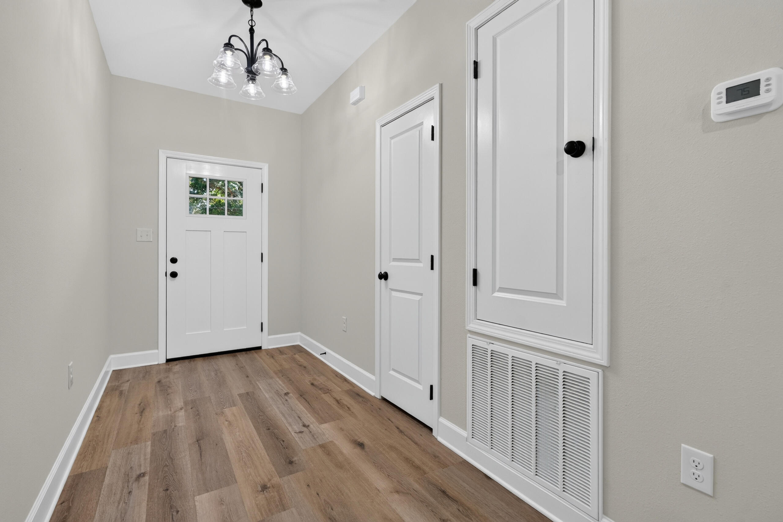 Entryway with wood-look flooring, a divided-light front door, and a large louvered HVAC return.