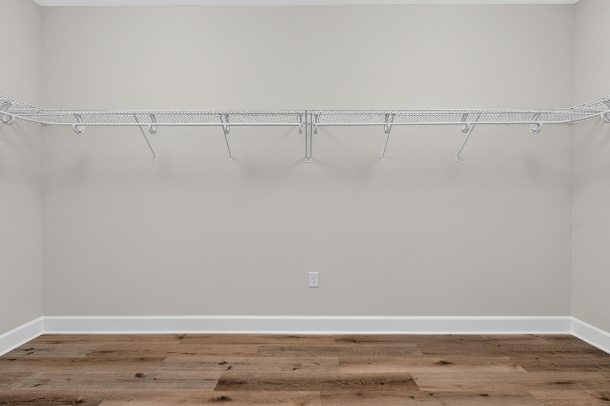 Empty closet with white wire shelving and wood-plank flooring.