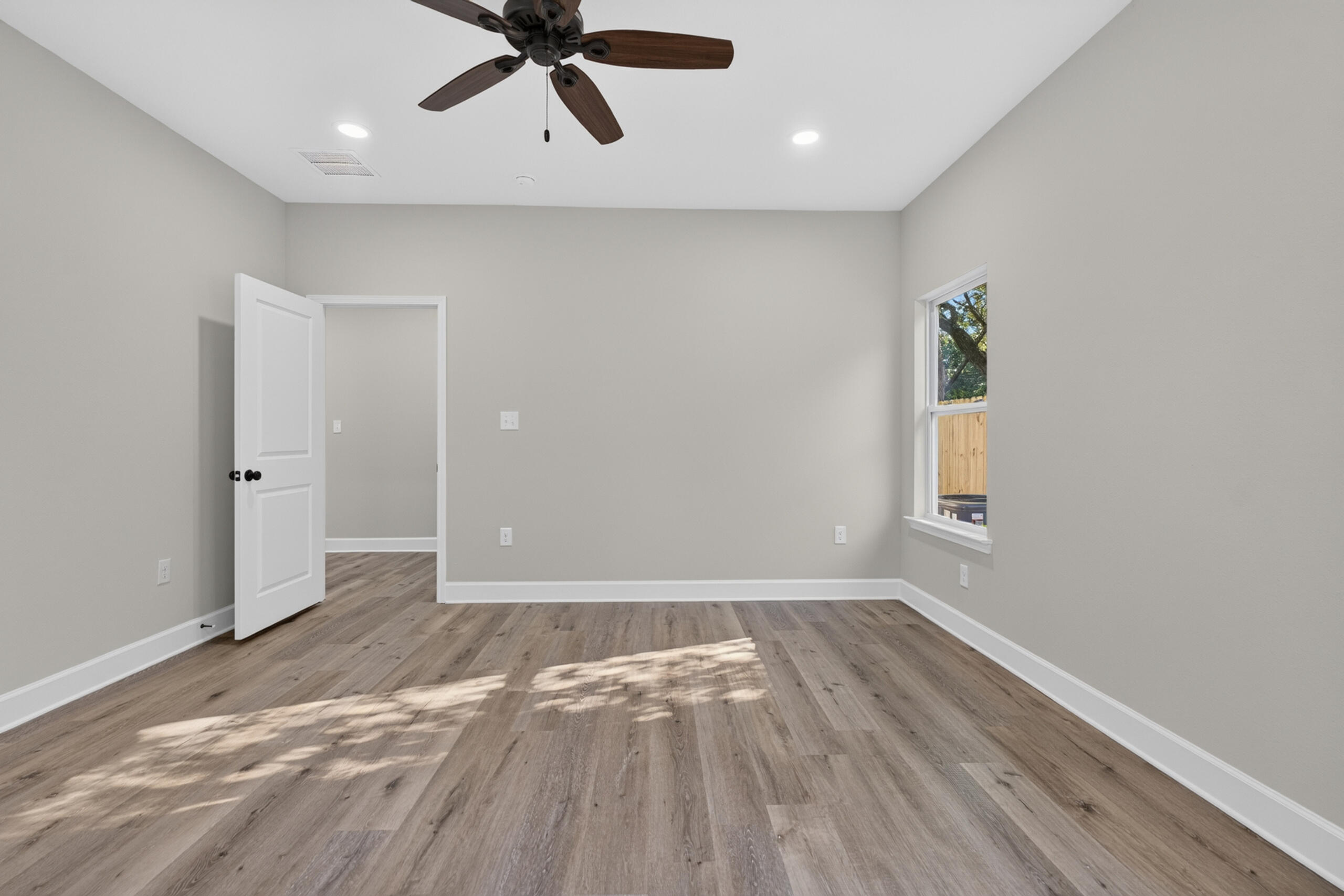 Empty room with wood-look plank flooring, a ceiling fan, and a window.