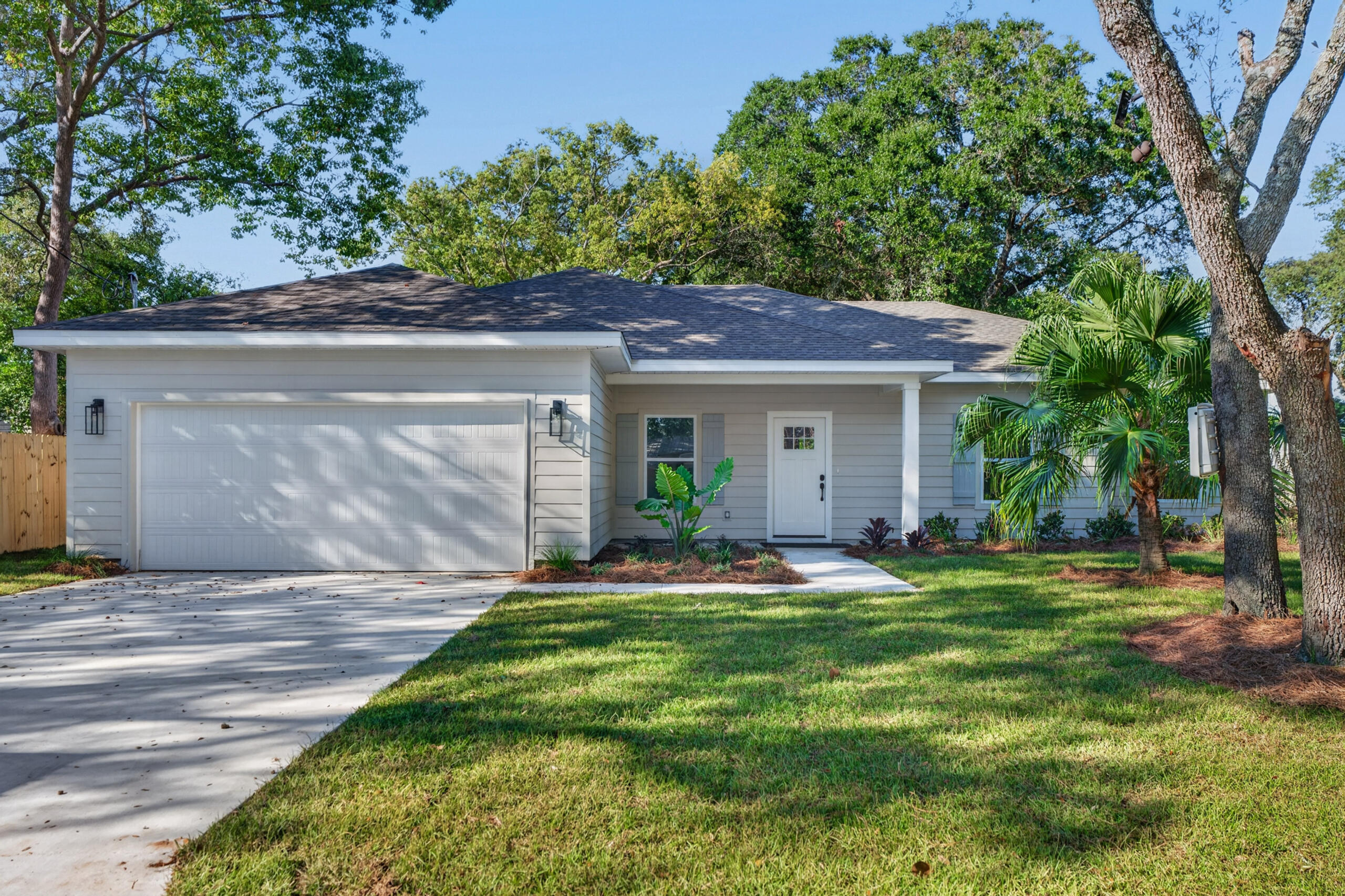 Single-story gray house with a wide garage, covered entry, and tree-shaded lawn.