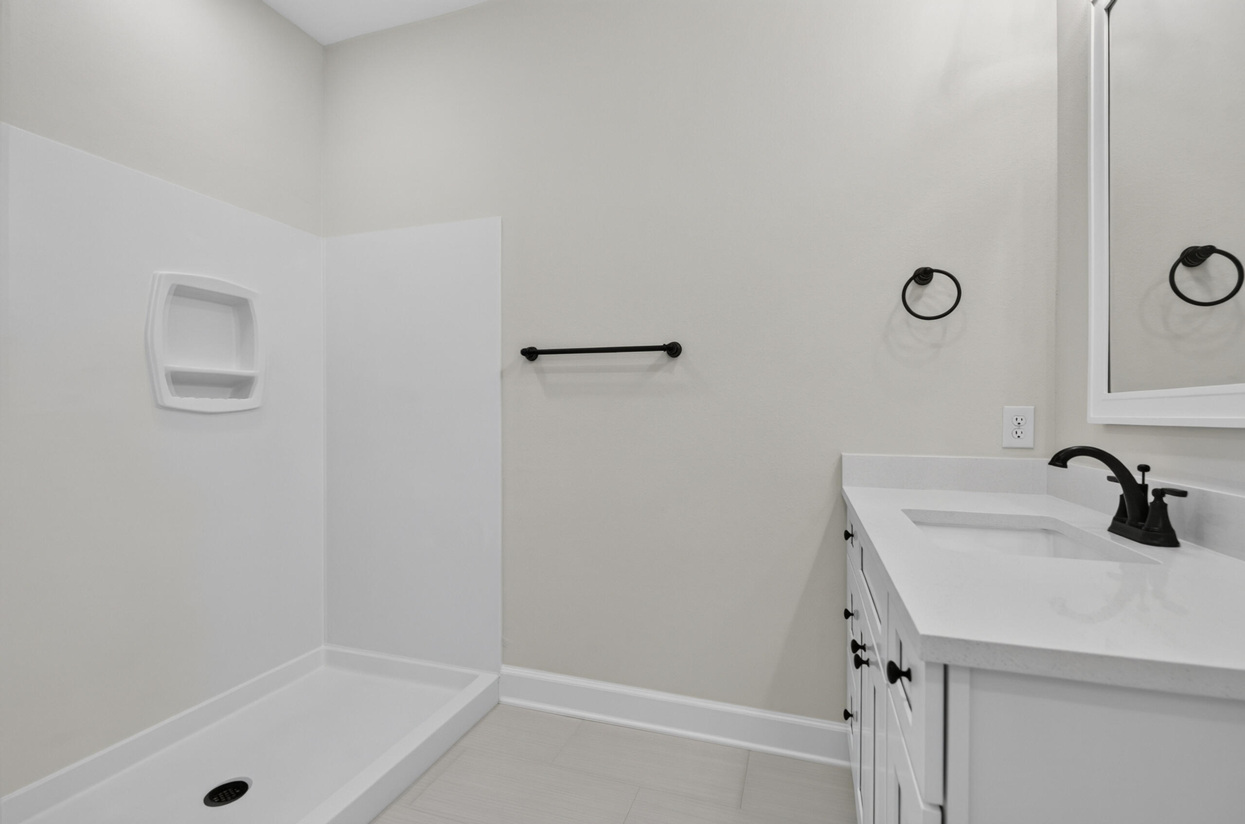 Bathroom with a white walk-in shower and vanity featuring black fixtures.