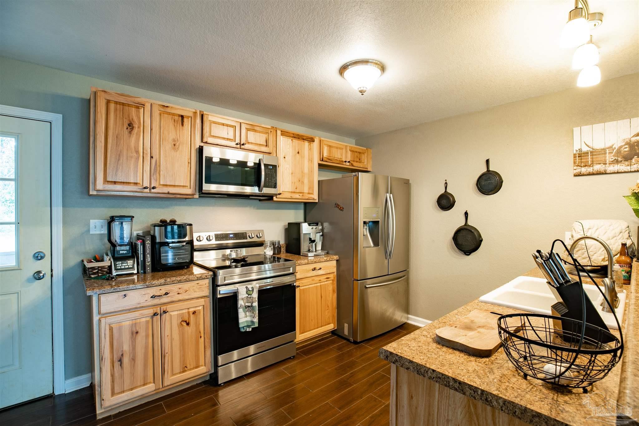 Kitchen with natural-wood cabinets, stainless appliances, granite counters, and a peninsula sink.