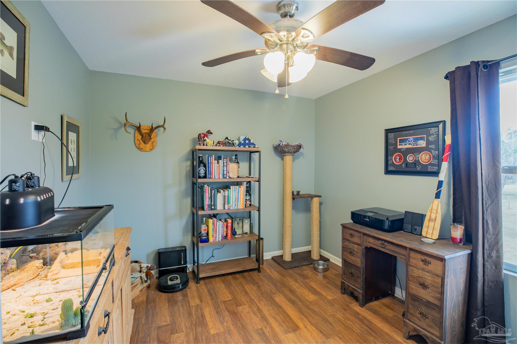 Furnished home office with a bookcase, aquarium, cat tower, and wooden desk.