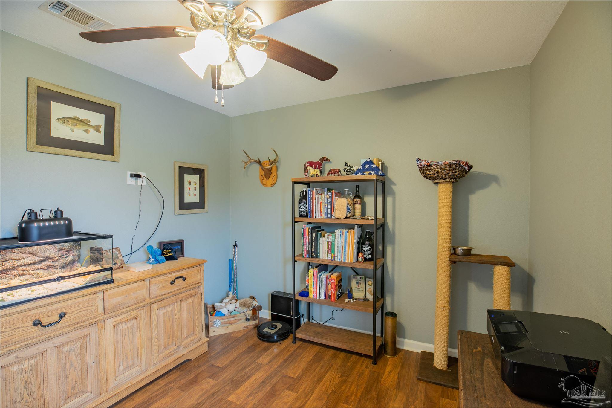 Furnished room with an aquarium cabinet, bookcase, cat tree, and wood flooring.
