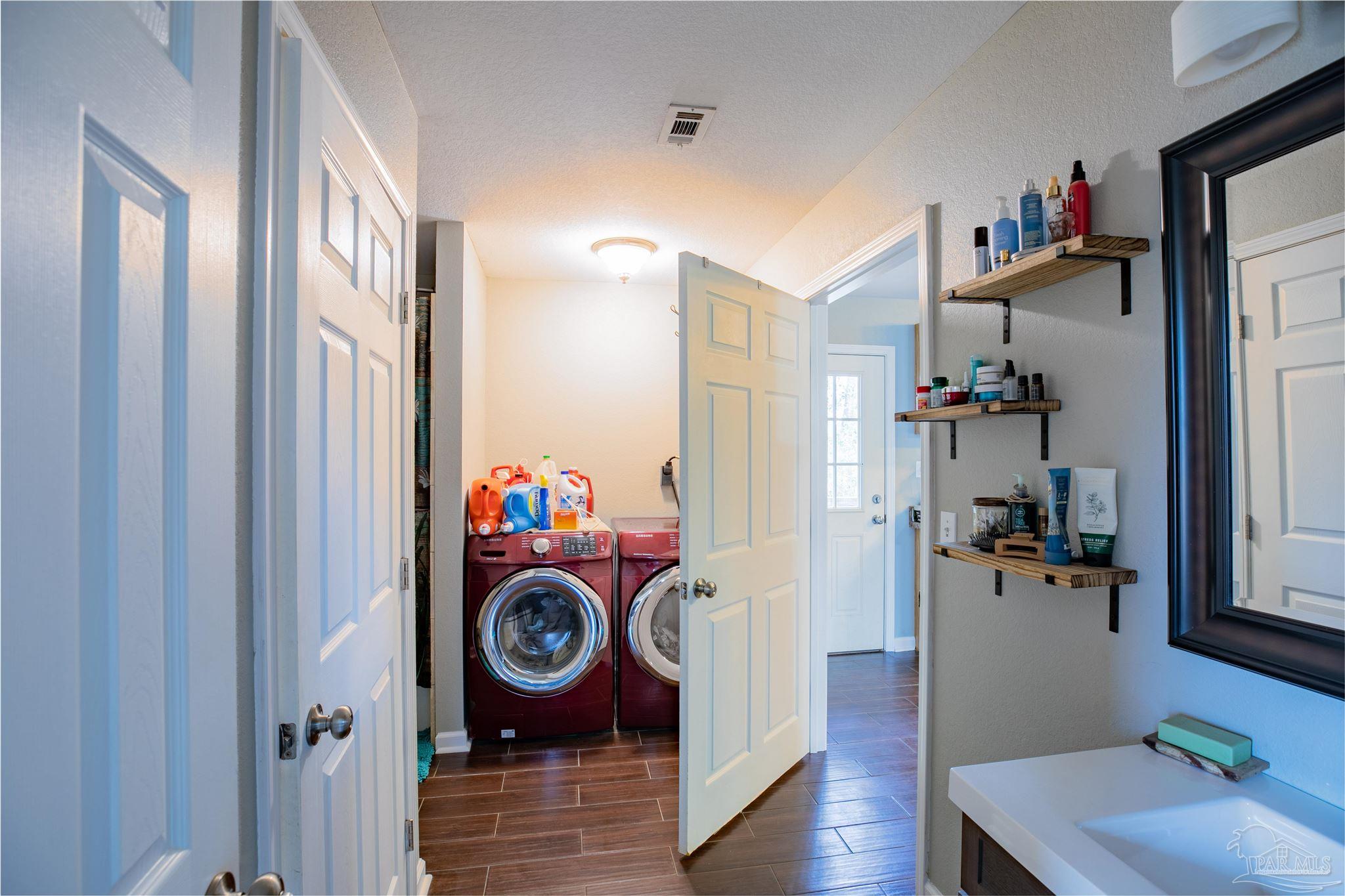 Laundry area with red front-loading washer and dryer beside a bathroom vanity.