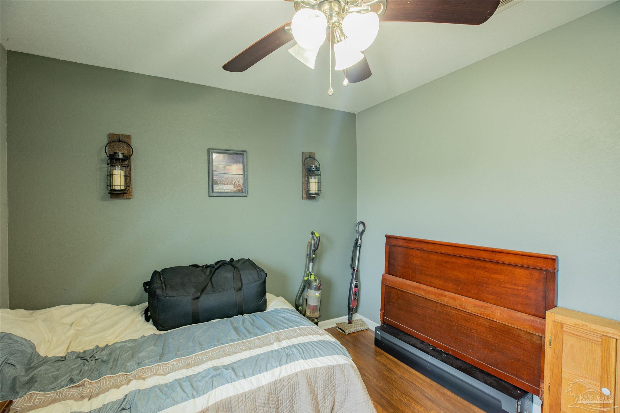 Bedroom with a wooden headboard, blue-and-cream bedding, and vacuums beside the bed.