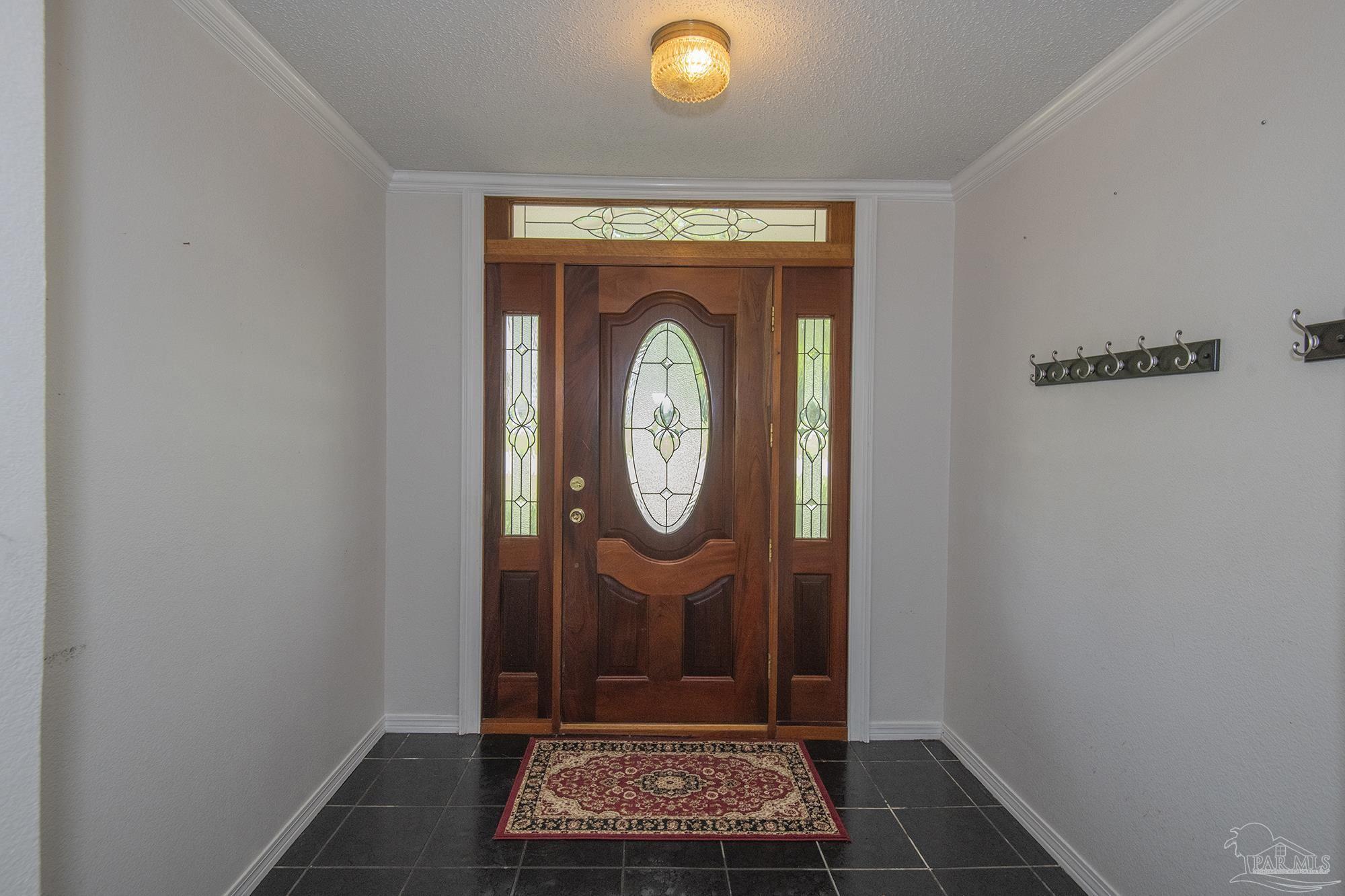 Entry foyer with a wooden front door featuring an oval stained-glass panel and matching sidelights.