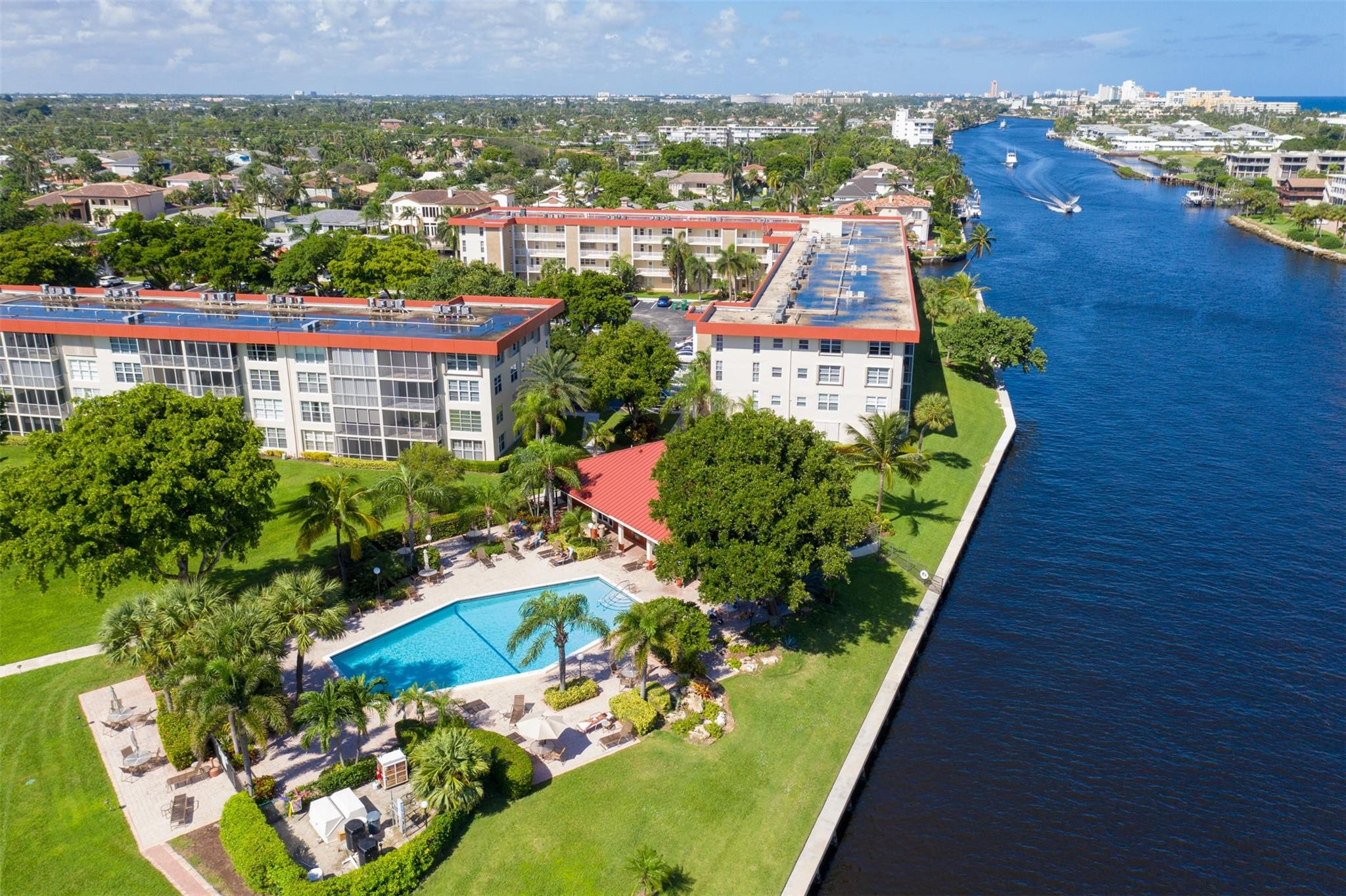 Waterfront condominium complex with a landscaped pool beside a wide canal.