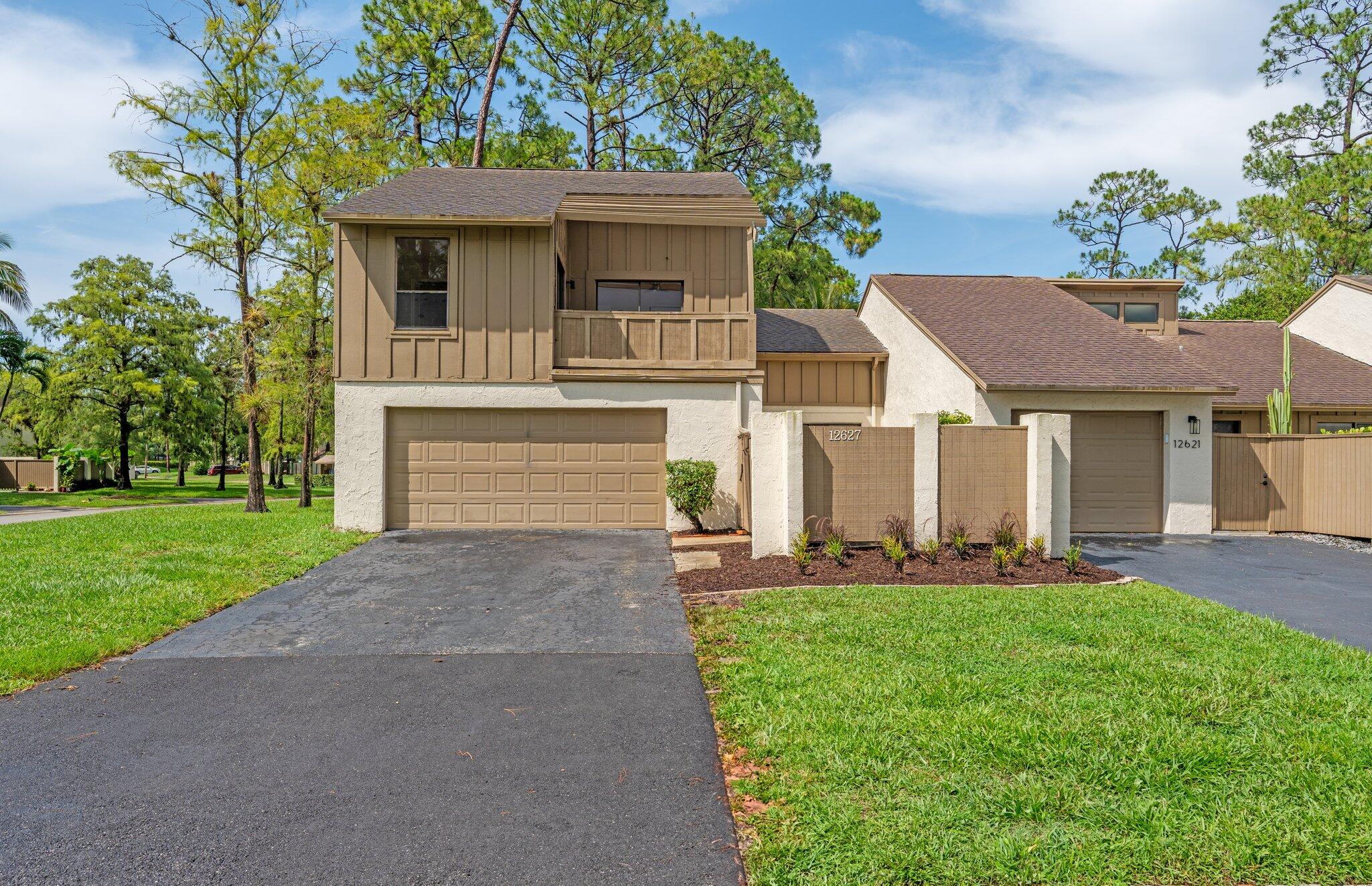 Tan two-story townhouse with a double garage and small balcony beside neighboring homes.