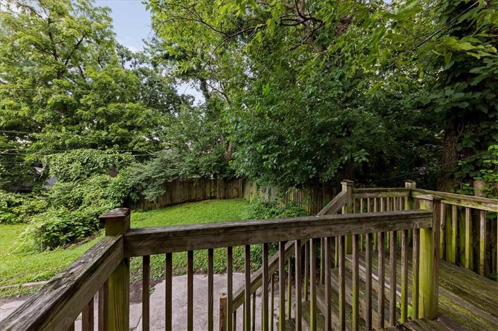 Wooden deck and stairs overlooking a leafy, fenced backyard.